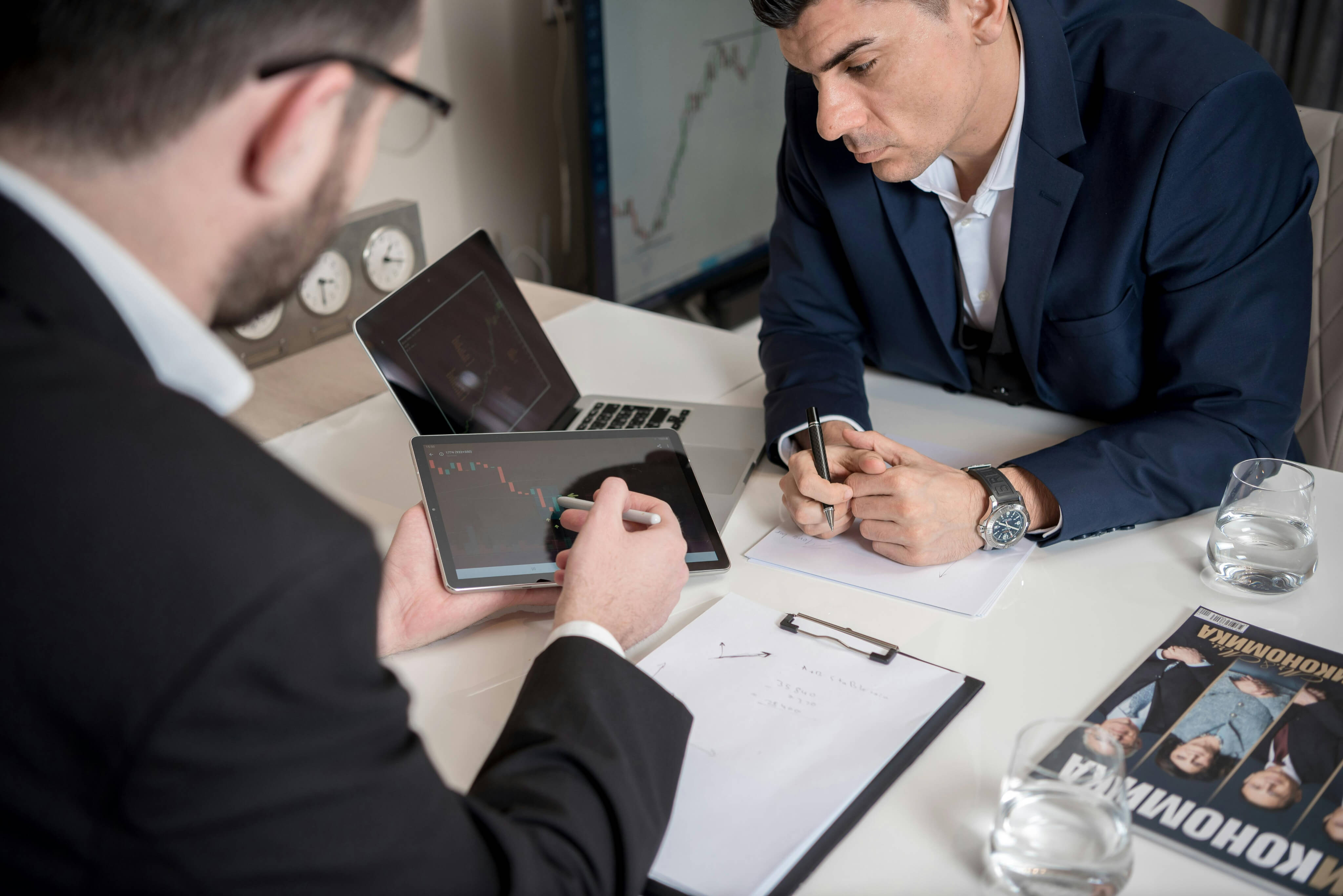 Two executives reviewing performance data on a tablet, symbolizing Barritus Capital’s commitment to disciplined capital allocation and insight.