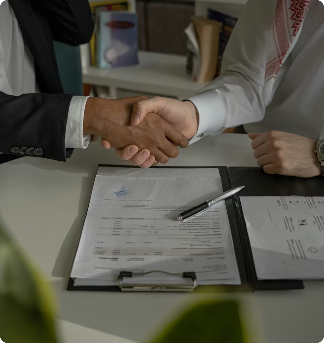 Close-up of a handshake over a clinical document, representing the evaluation and growth of healthcare businesses through strategic partnership.