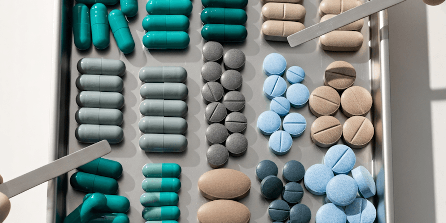 A selection of medical capsules and tablets, representing the shift from traditional pharmaceuticals toward regenerative biologic therapies.