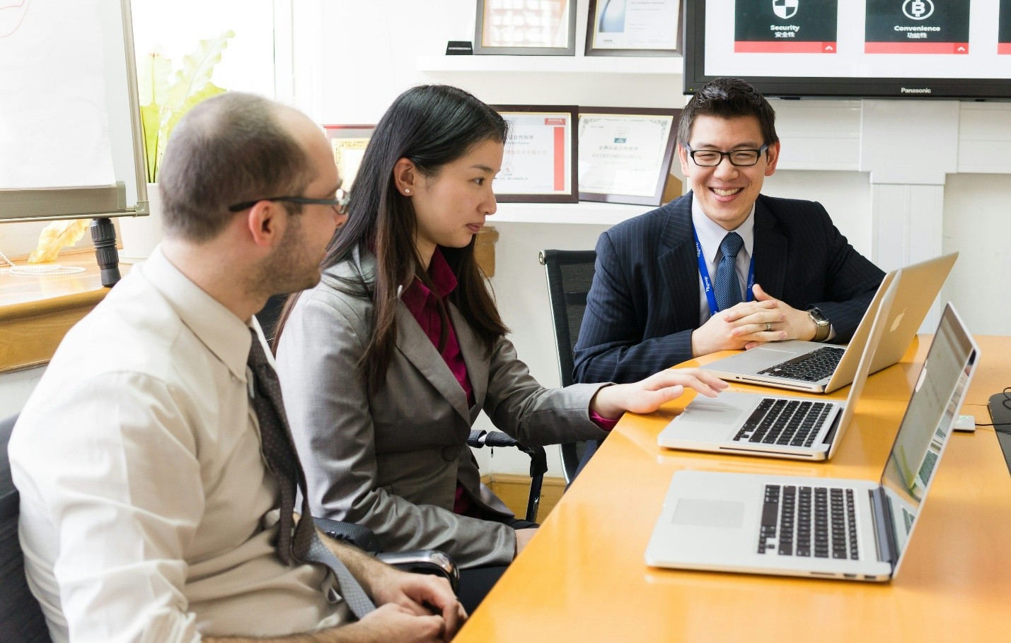 Three professionals in a meeting with laptops, representing investment diligence, evaluation, and strategic healthcare partnerships.