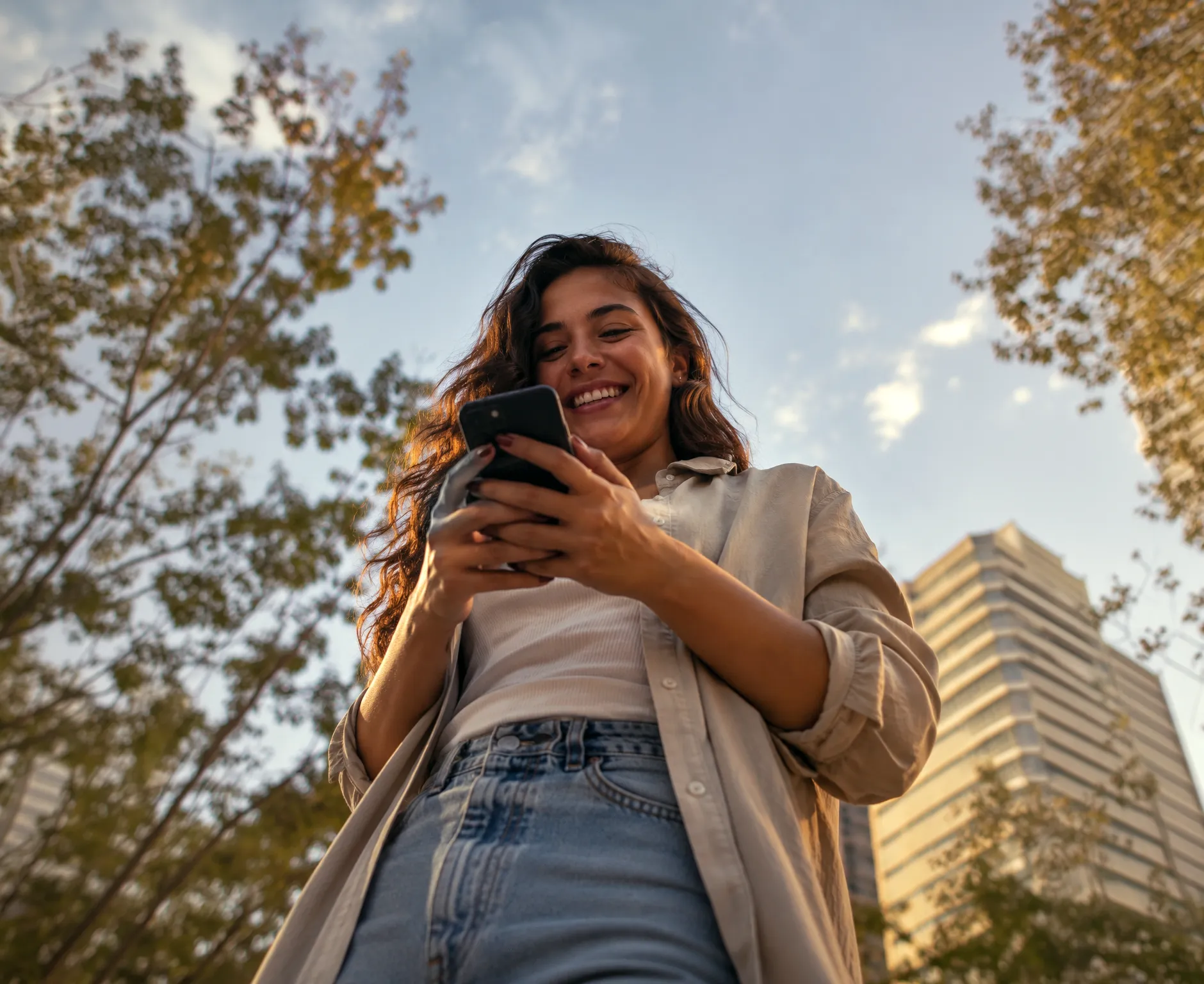 Smiling woman using her phone outdoors