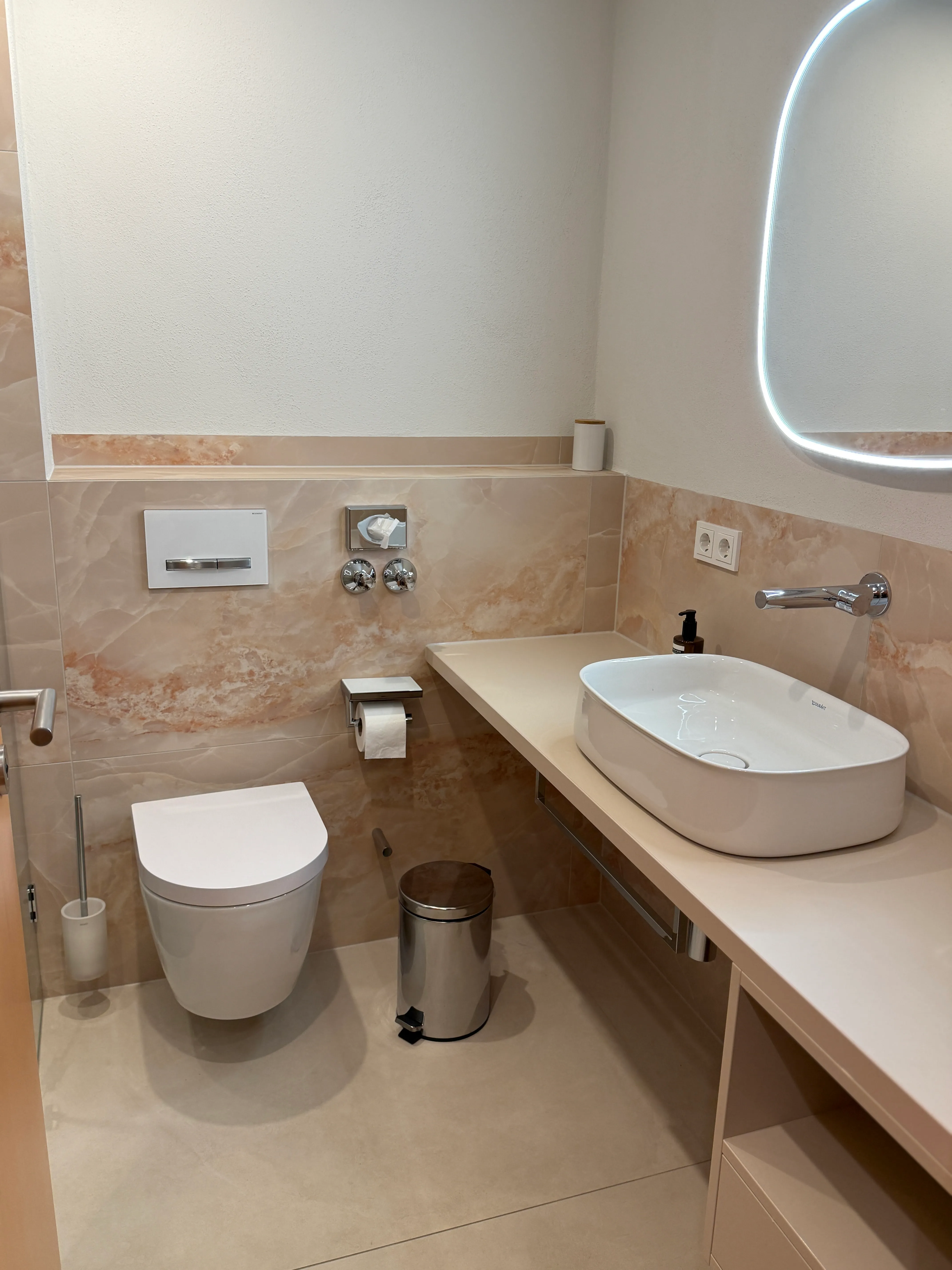 Modernes Gäste-WC mit beige marmorierten Großformatfliesen in Quarzsand-Optik und Aufsatzwaschbecken