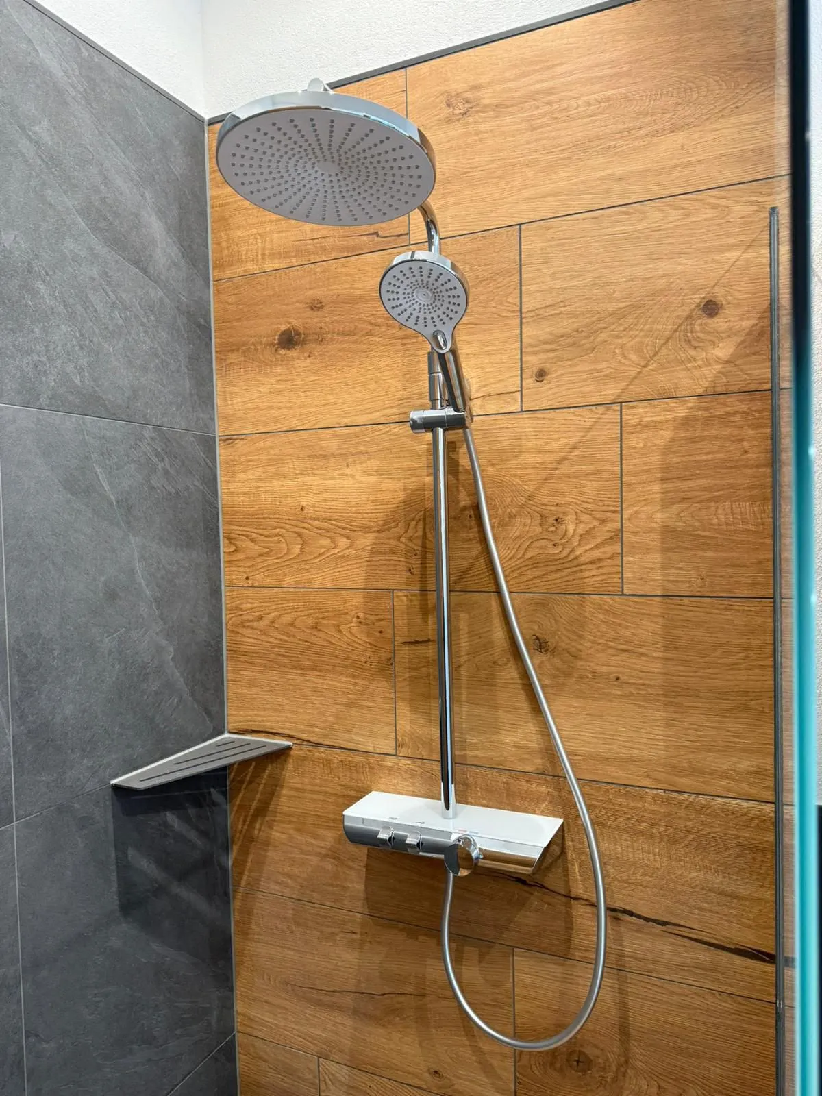 Walk-in-Dusche mit Regenbrause, Duschrückwand in Holzoptik und Seitenwand in dunkler Schieferoptik