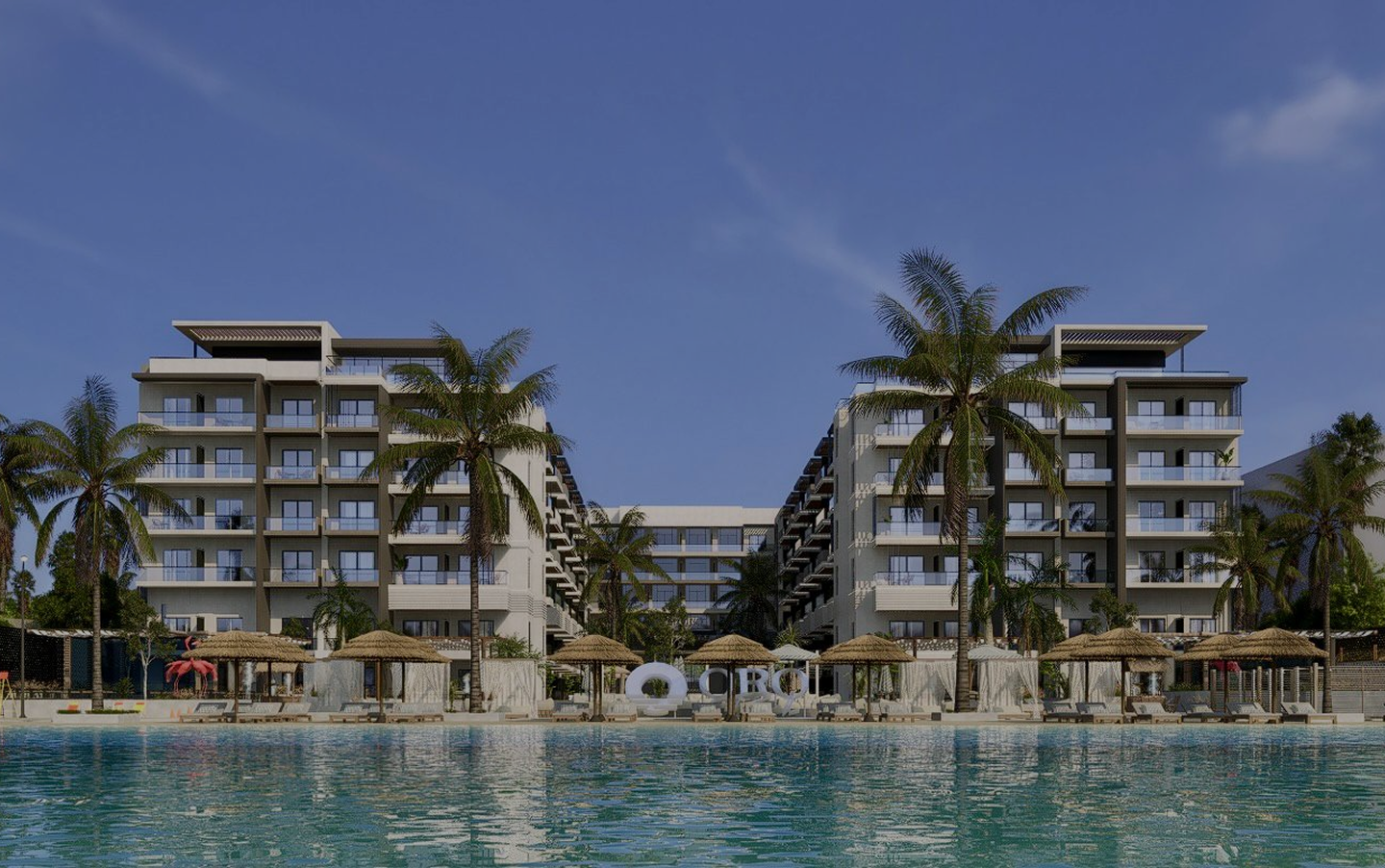 Modern beachfront resort with two six-story buildings, palm trees, thatched umbrellas, lounge chairs, and a large swimming pool in the foreground.