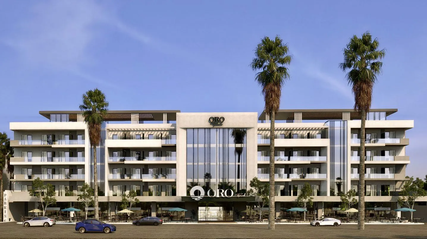 Modern five-story building named ORO with large glass windows, balconies, palm trees, and parked cars in front.