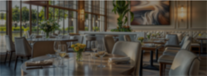 Elegant restaurant interior with tables set with glasses, napkins, and floral centerpieces.