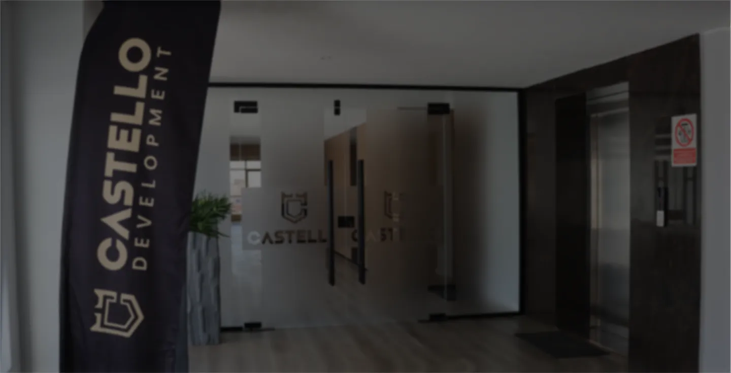Office entrance with frosted glass doors labeled CASTELLO and a black vertical banner with CASTELLO Development text.