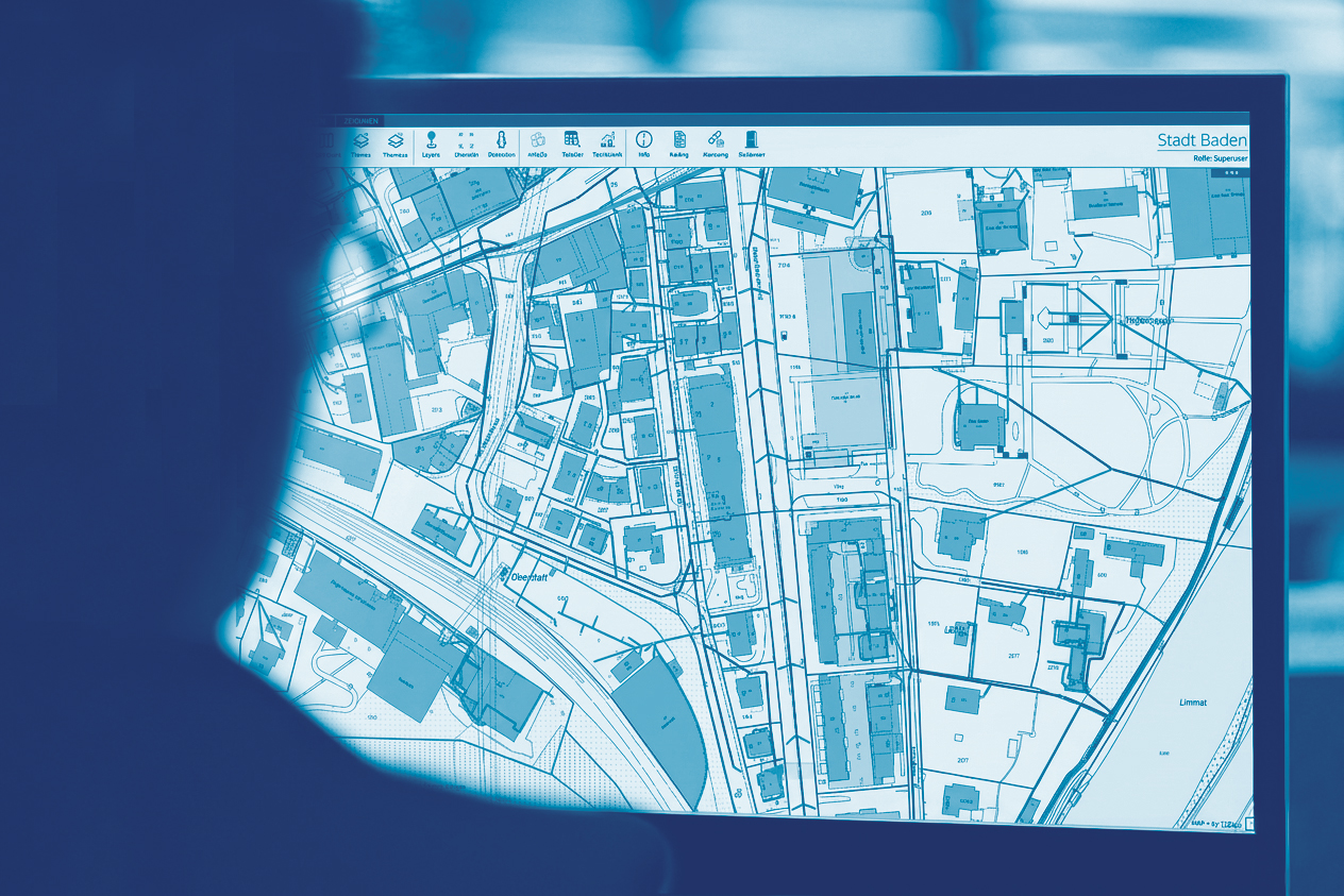 Person betrachtet digitalen Stadtplan von Baden auf einem Bildschirm mit Straßen, Gebäuden und Fluss Limmat.