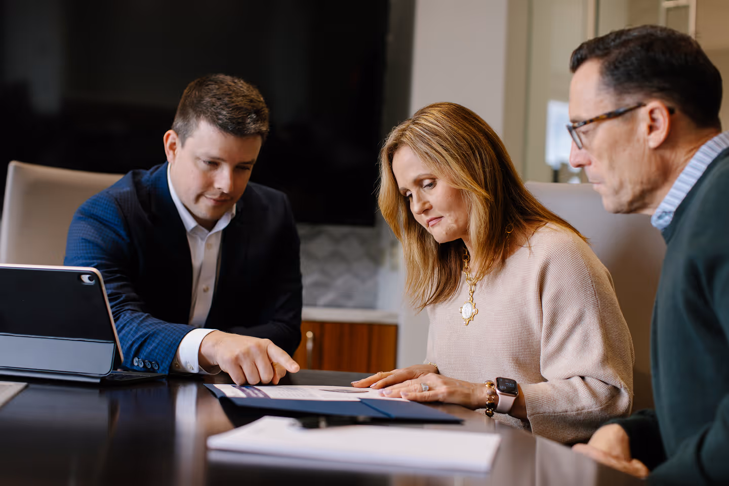Three business professionals reviewing a document together at a conference table.