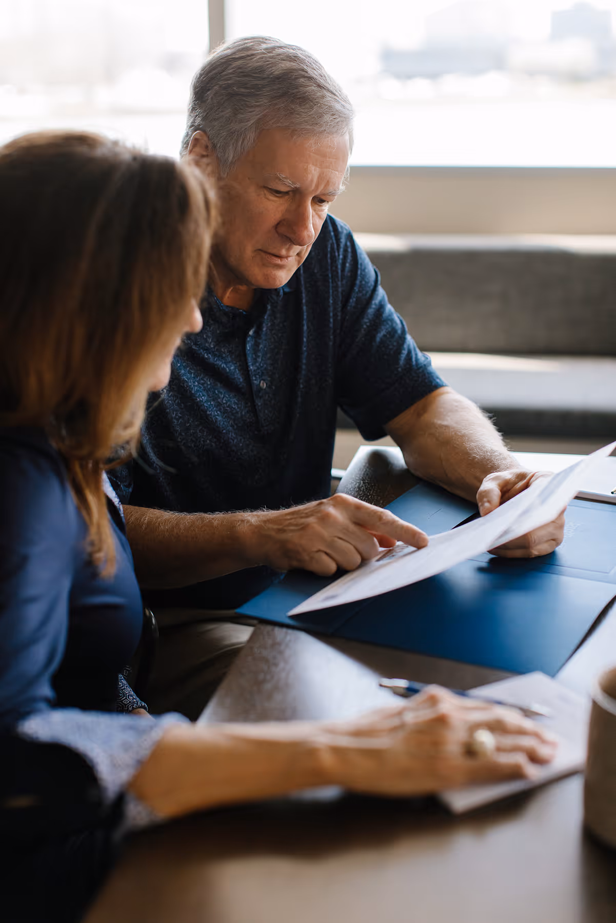 Two adults, a man and a woman, sitting at a table reviewing documents together.