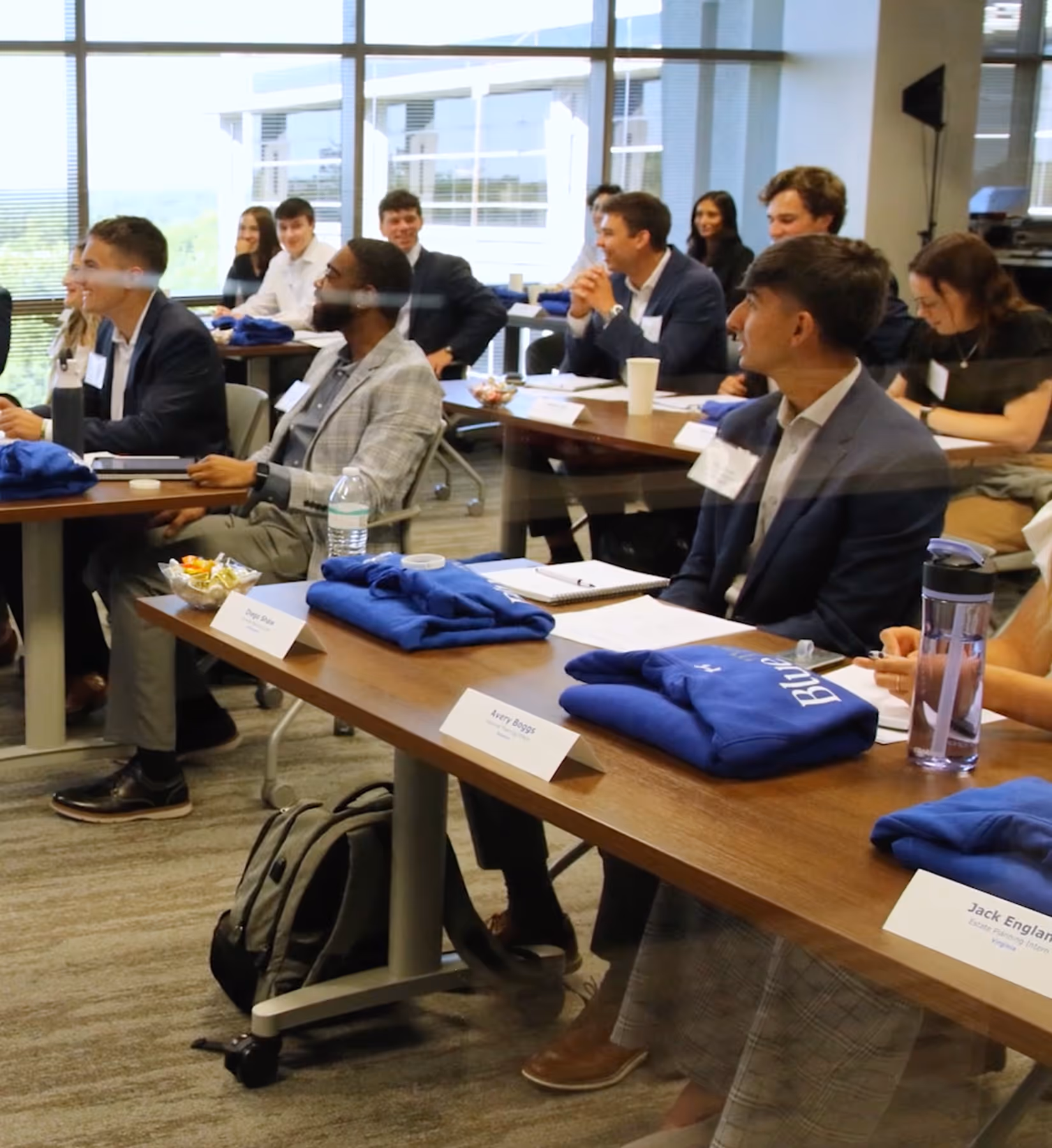 Young professionals sitting in a conference room with name tags and blue shirts on the tables.