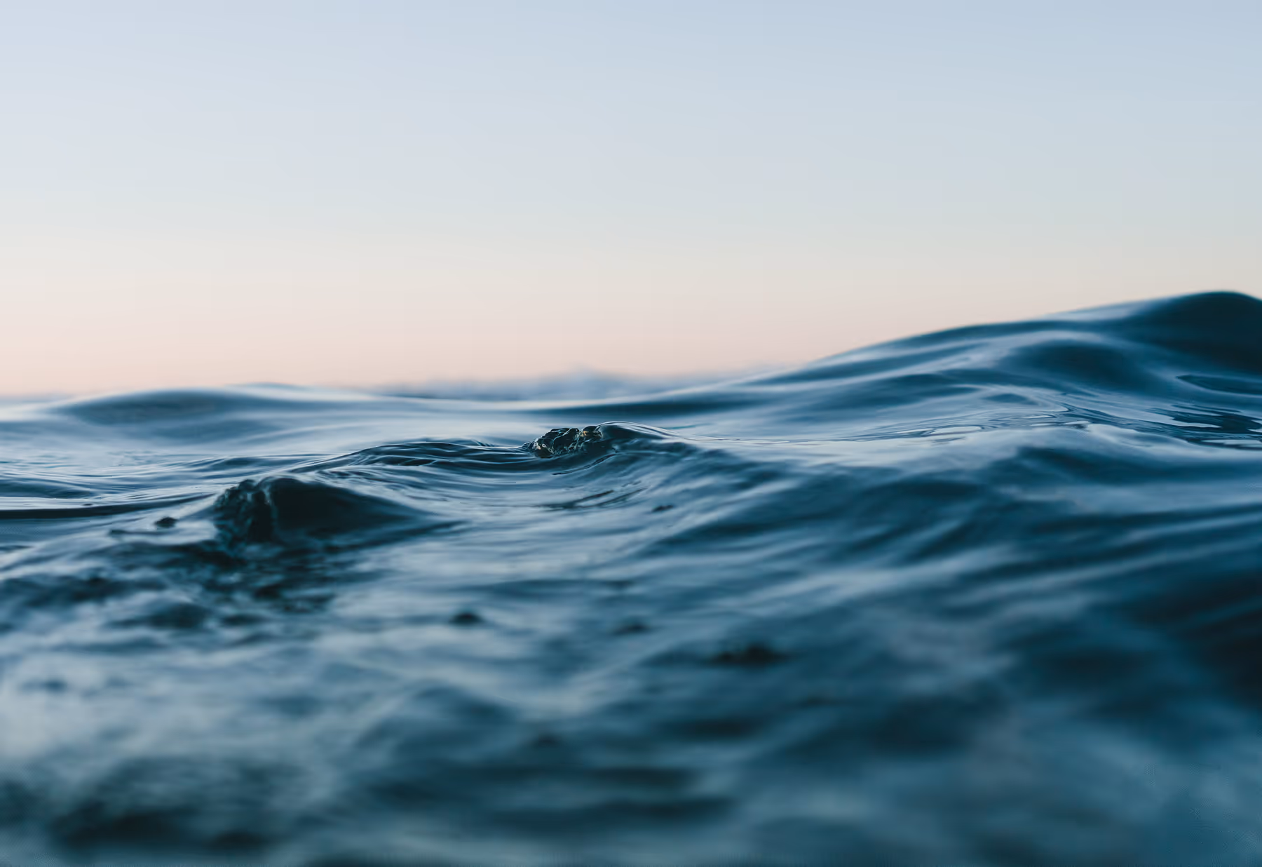 Close-up of gentle ocean waves under a clear sky at dawn or dusk.