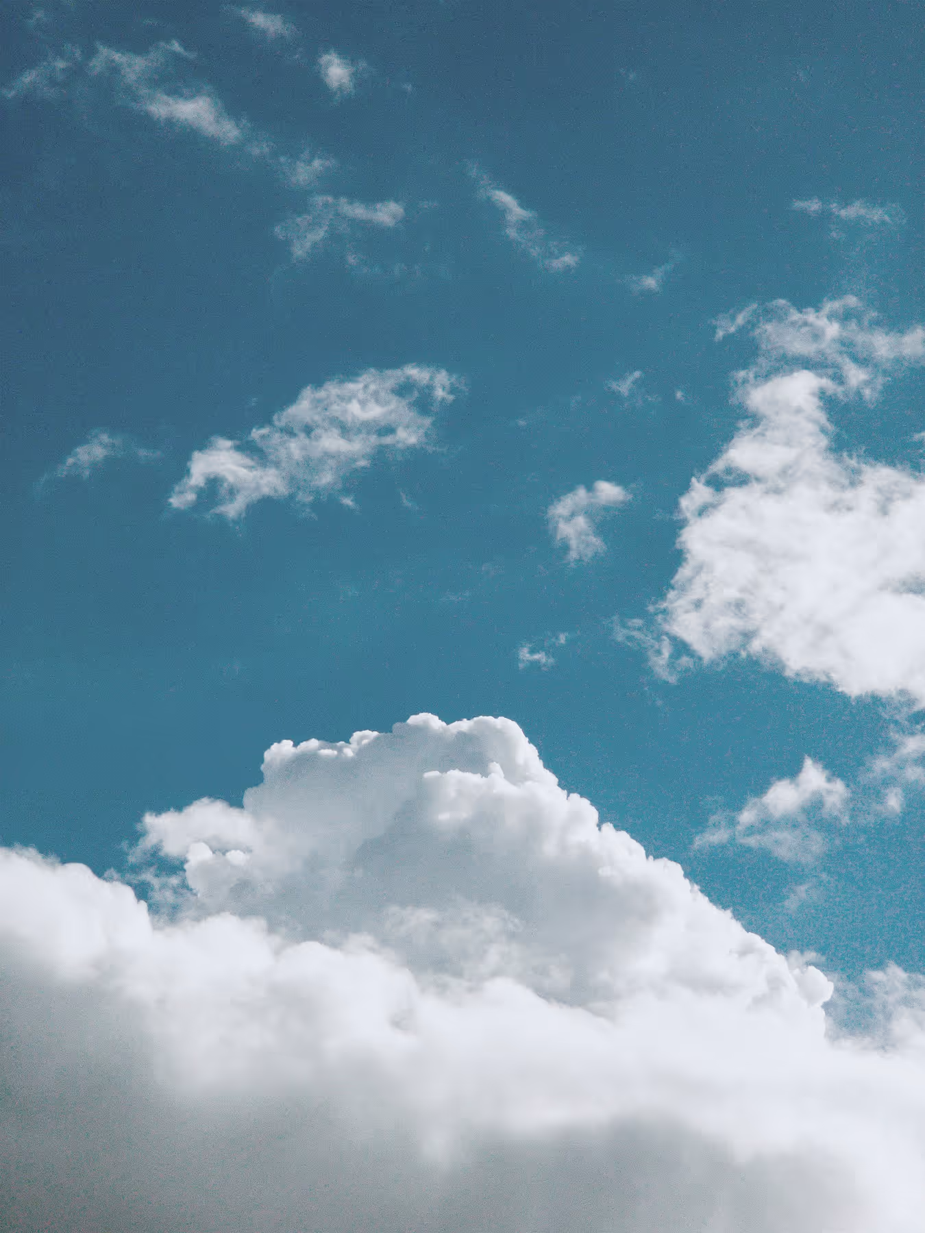 White fluffy clouds against a clear blue sky with smaller clouds scattered above.