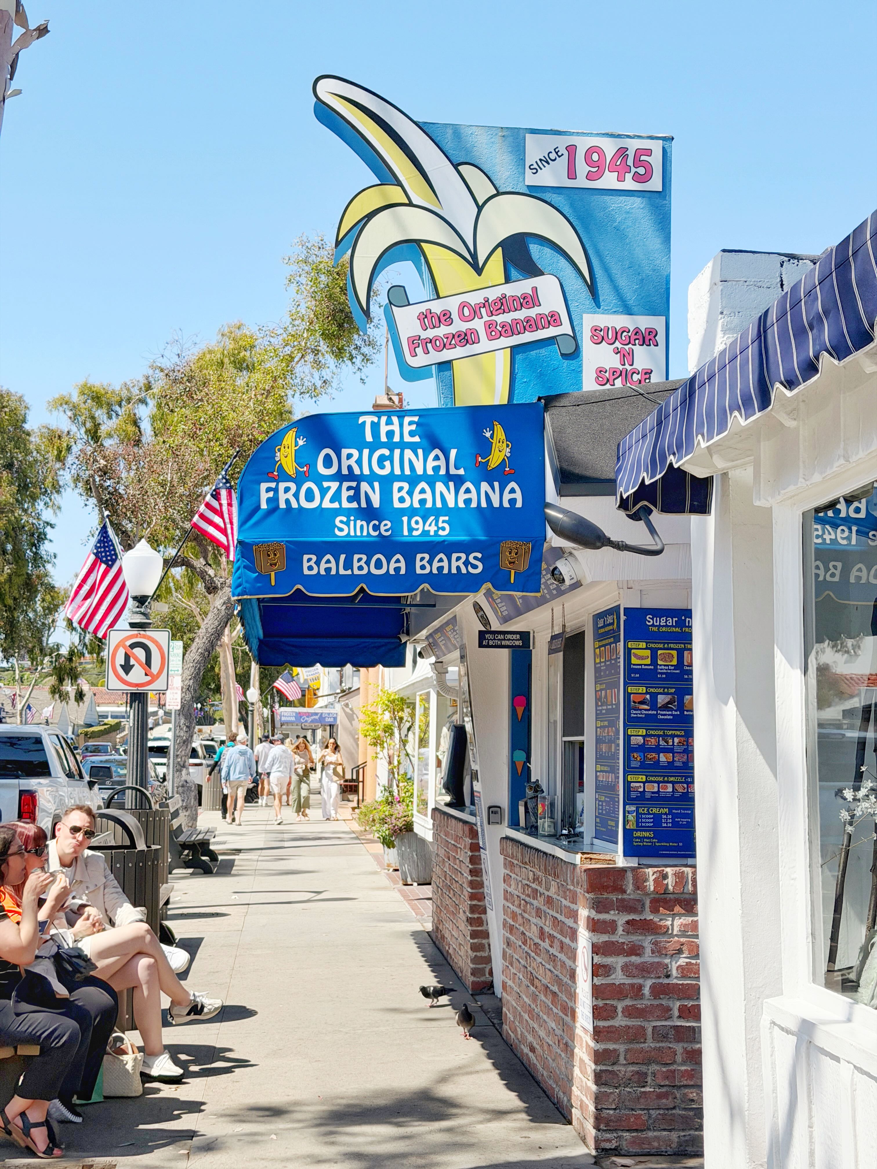 Sugar 'n Spice on Balboa Island — the 1945 blue and yellow frozen banana stand on Marine Avenue with a hand-painted Original Frozen Banana mural sign above blue and white striped awning
