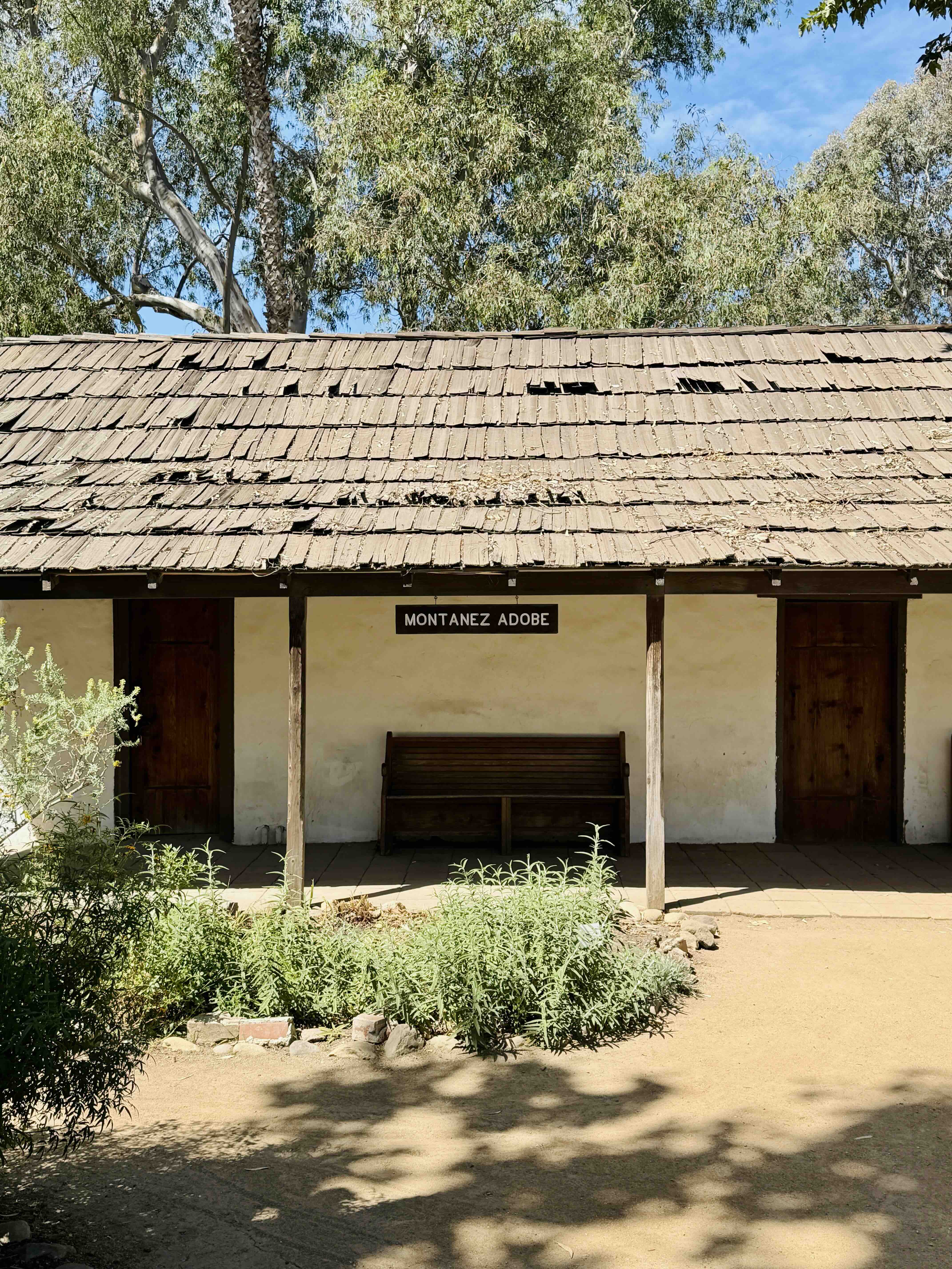 The Montañez Adobe at 31745 Los Rios Street in San Juan Capistrano, shrouded in early-morning coastal fog. The two-foot-thick 1794 adobe walls and weathered wood trim emerge from a soft gray mist.
