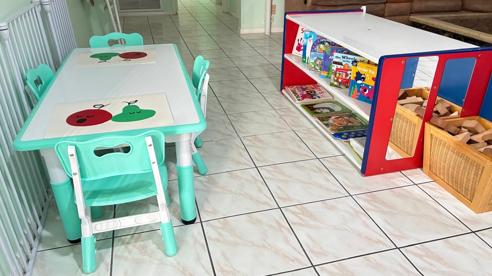 Indoor reading table with a low bookshelf and blocks at Little Genius Home Daycare OC.