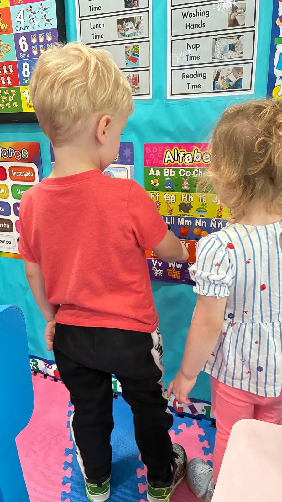 Indoor early-learning wall with alphabet and daily routine charts at Little Genius Home Daycare OC.