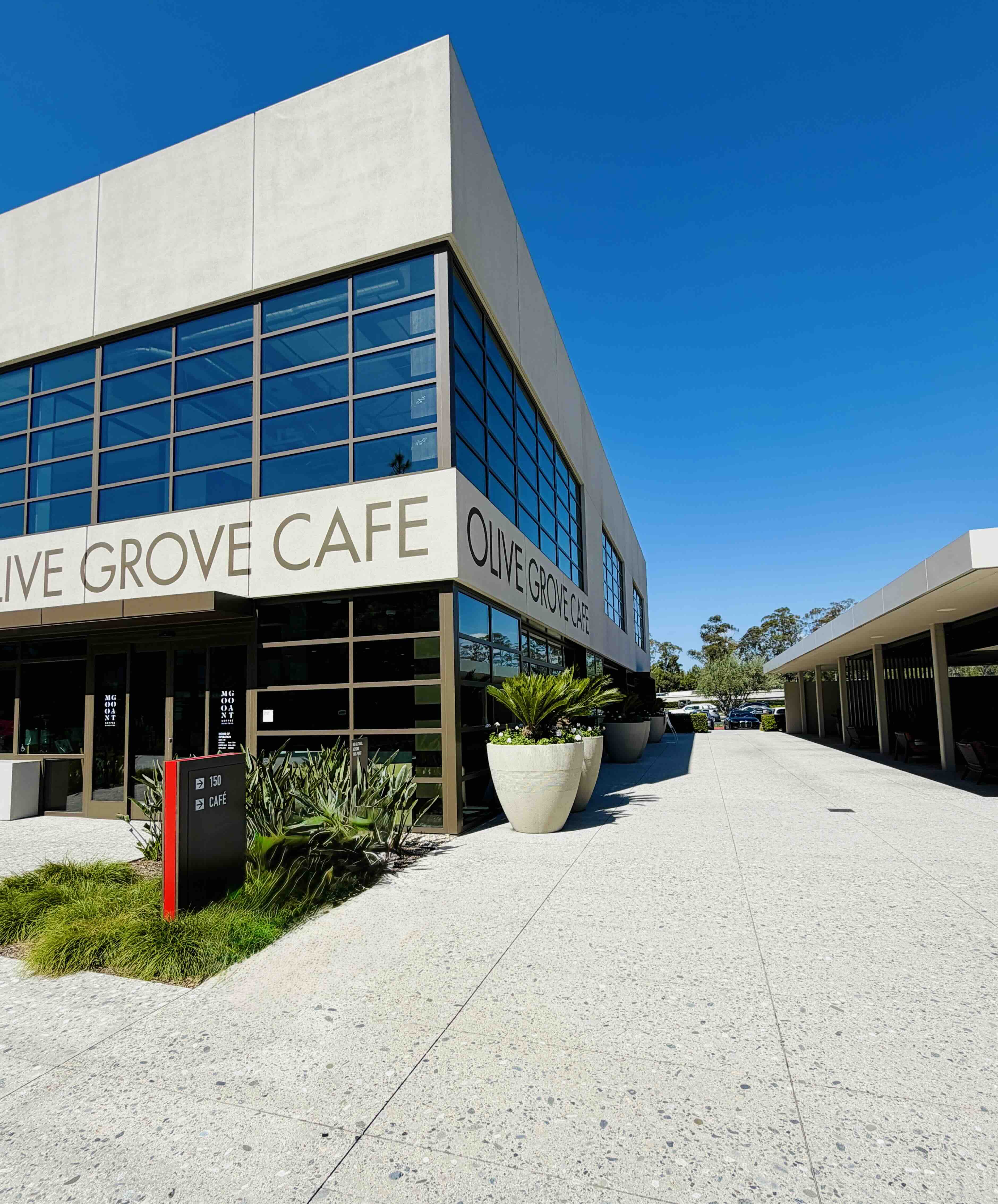 Olive Grove Cafe exterior signage at Innovation Office Park in Irvine, showing the OLIVE GROVE CAFE storefront entrance under a covered walkway.