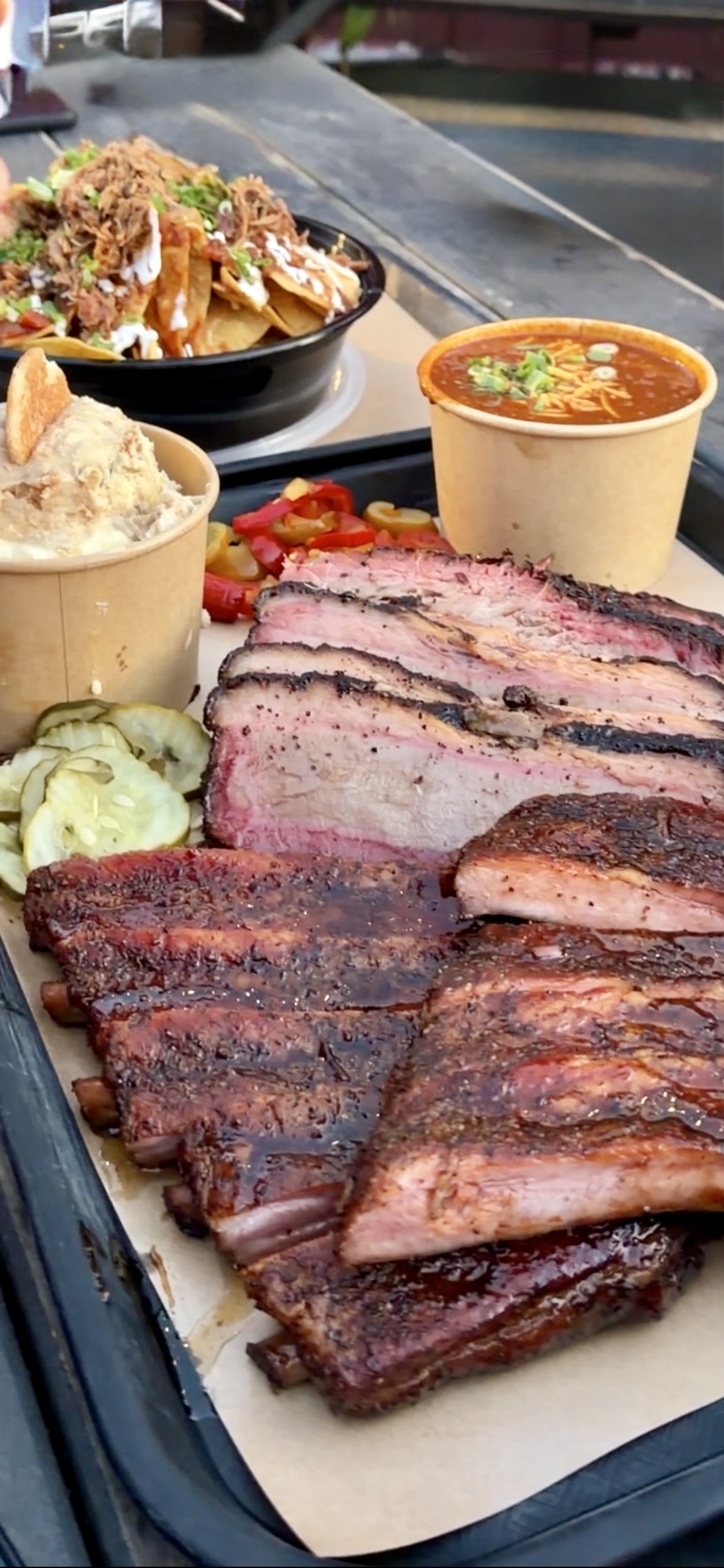 Heritage Barbecue plate at San Juan Capistrano — sliced brisket, beef ribs, and banana pudding served on butcher paper.