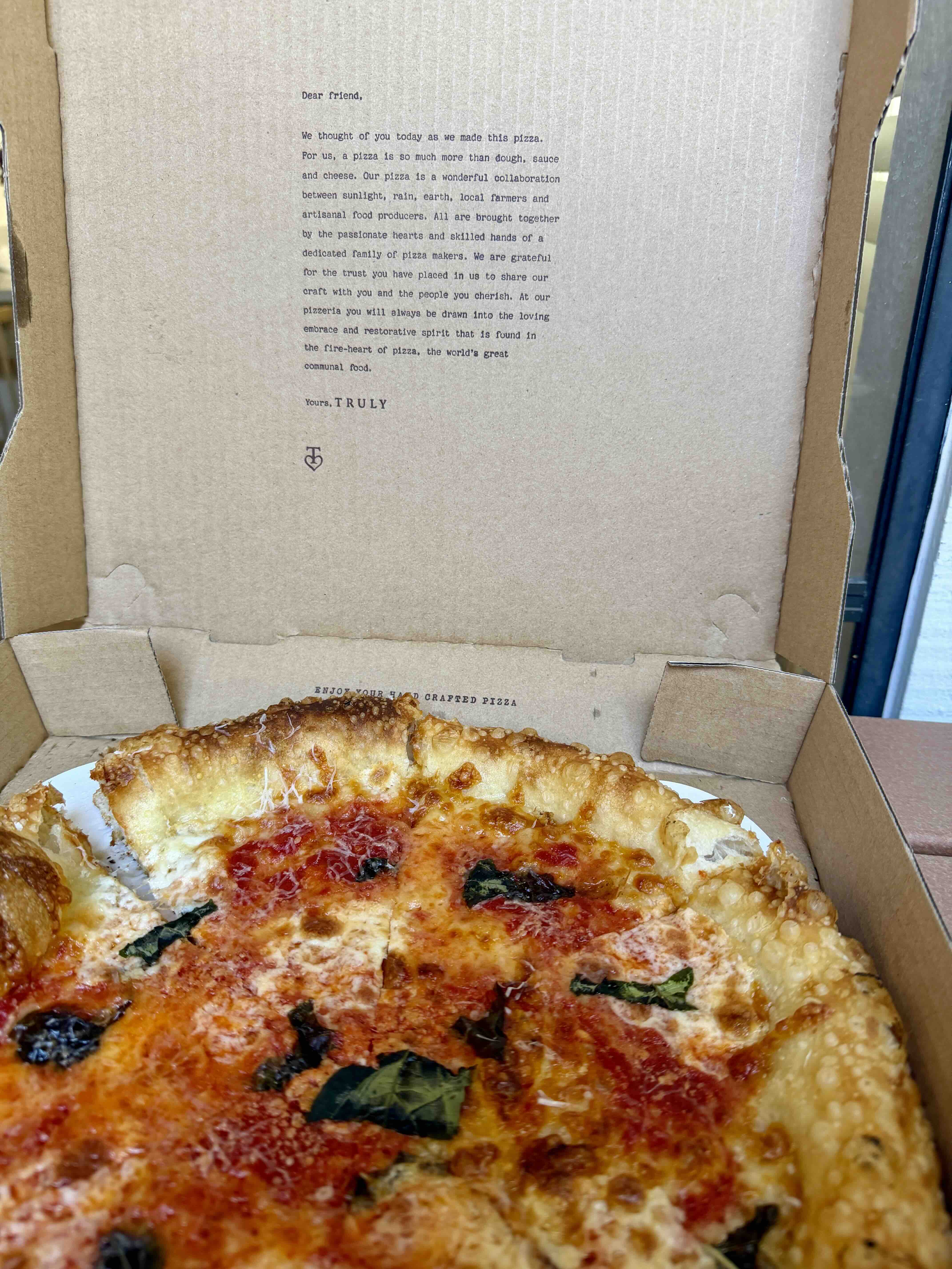 Freshly baked pizza in an open takeout box from Truly Pizza in Dana Point.