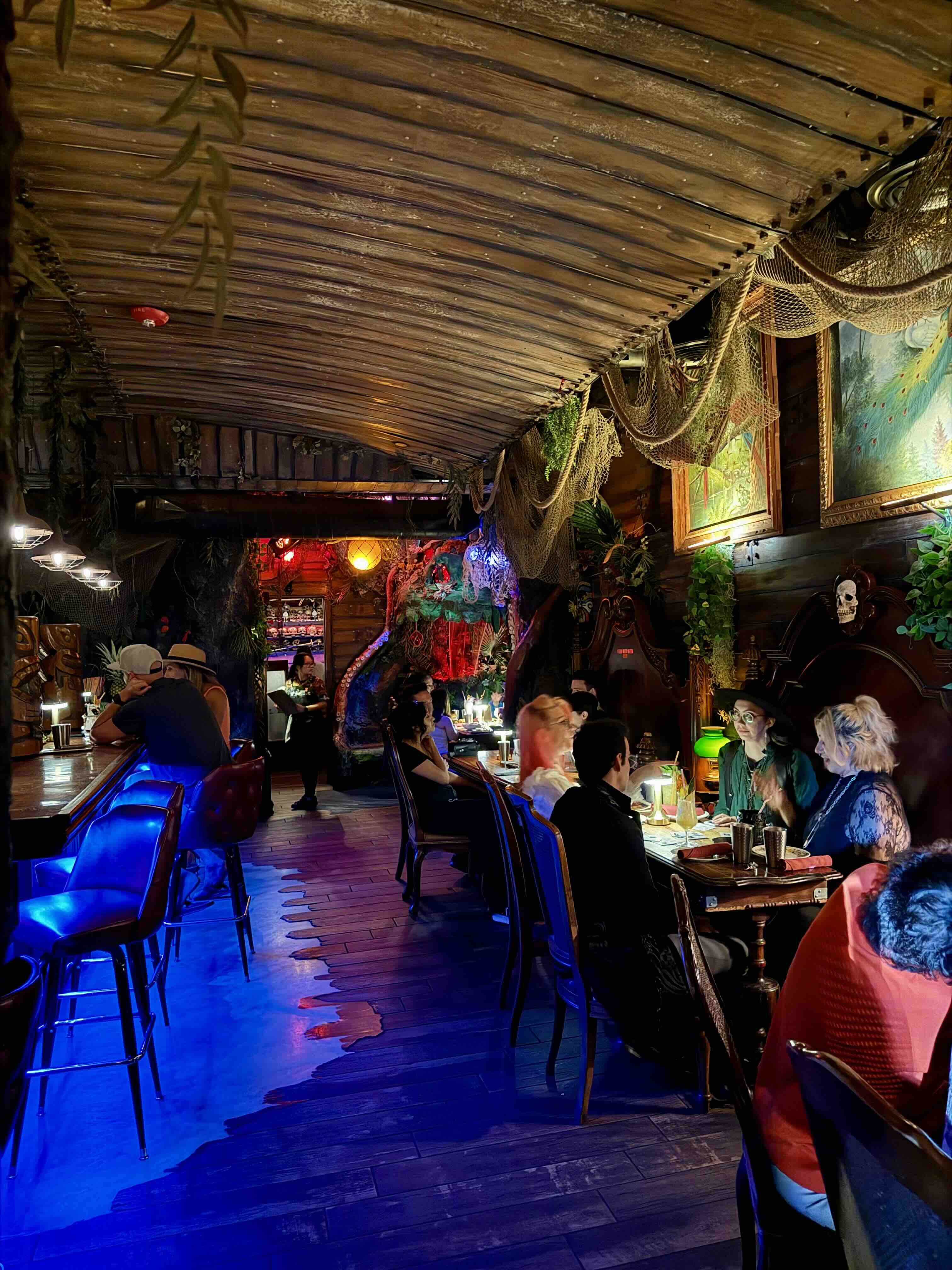 Sunken-ship interior at Strong Water in Downtown Anaheim, with dark wood, nautical artifacts, and lantern lighting.