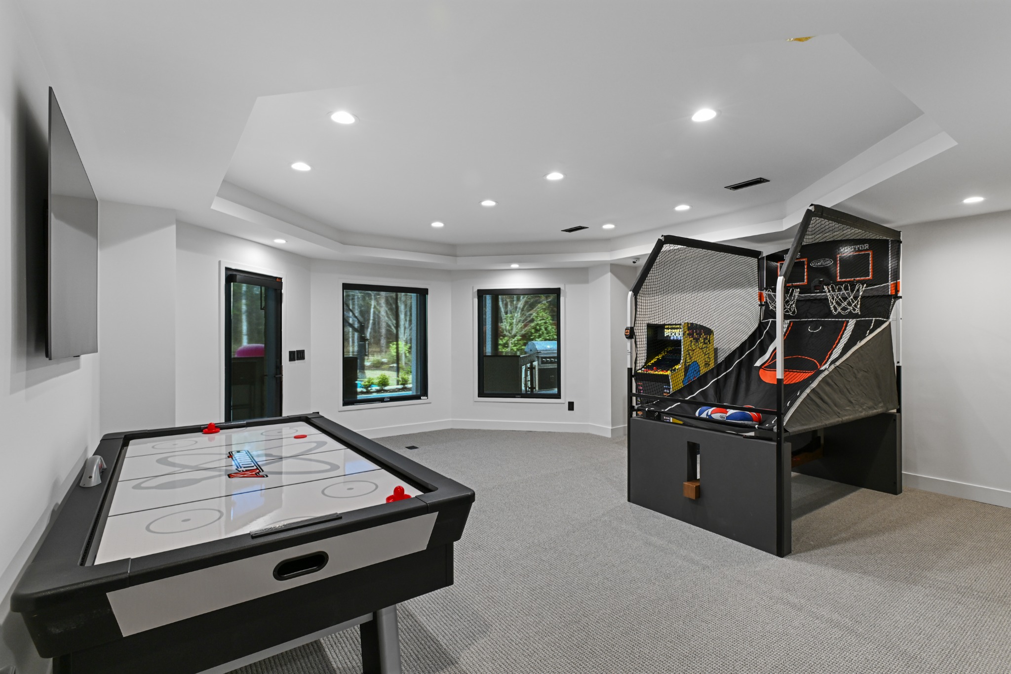 Finished basement game room with air hockey, basketball arcade, and entertainment wall
