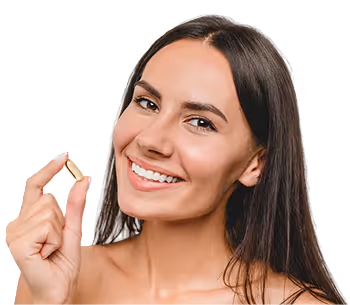 Smiling woman with long hair holding a small pill between her fingers against a black background.