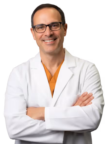 Smiling man wearing glasses and a white lab coat with arms crossed, looking at the camera.