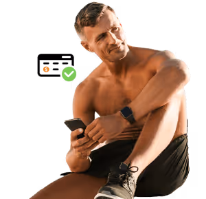 Fit man in workout clothes checking phone, sitting with one knee up and wearing a smartwatch.
