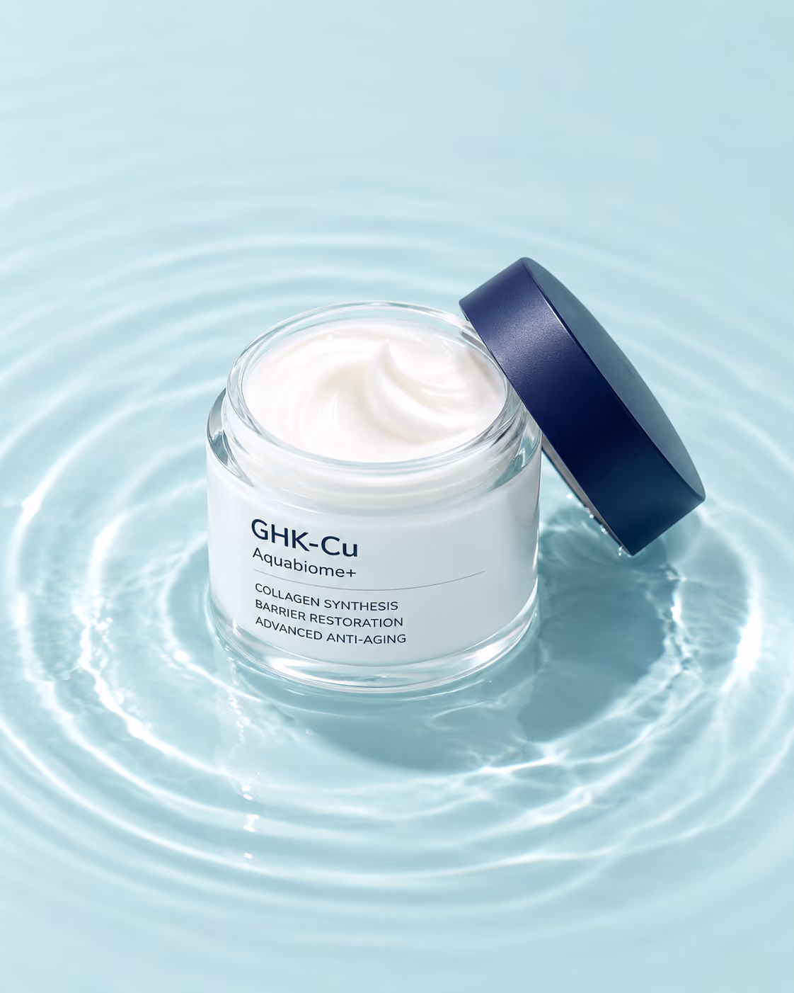 GHK-Cu Aquabiome+ cream jar with a navy lid standing in shallow rippling water against an aqua wall