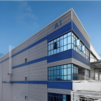 Portrait of a man in a dark suit and light blue tie against a grey background.