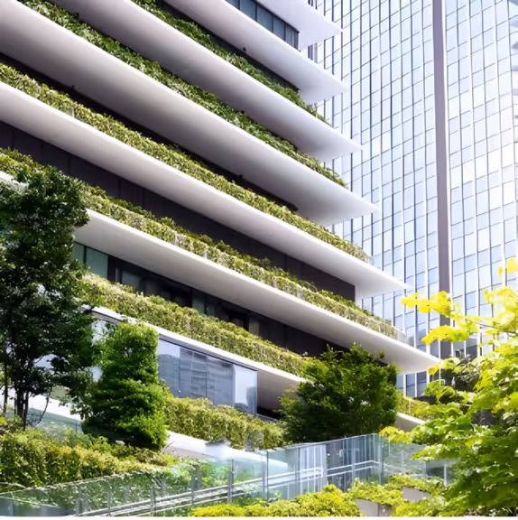 Modern building facade with multiple horizontal green terraces and surrounding trees.