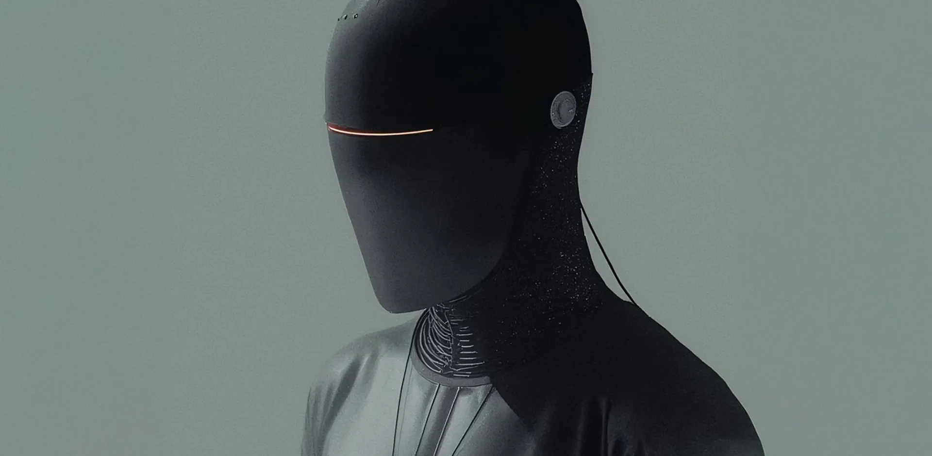Futuristic humanoid robot with a smooth black helmet and a thin horizontal glowing line where the eyes would be, against a plain gray background.