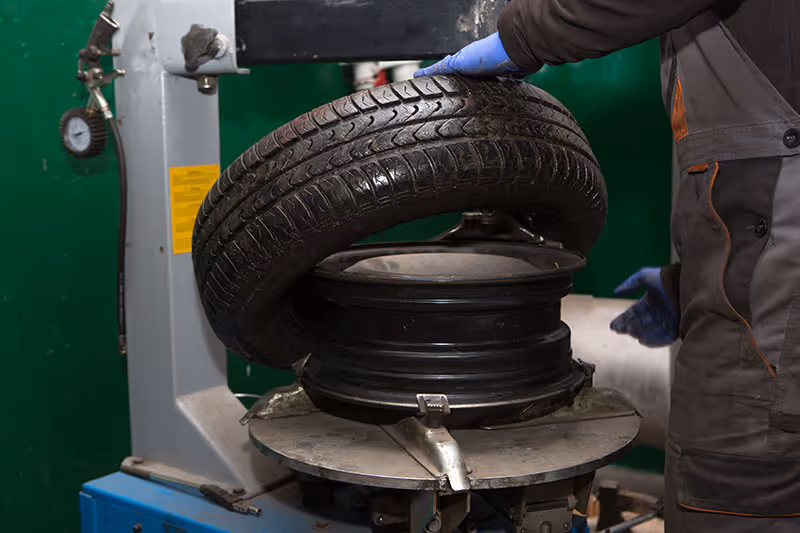 Mechanic fitting and balancing a new tyre on a wheel at a Masterton tyre service workshop