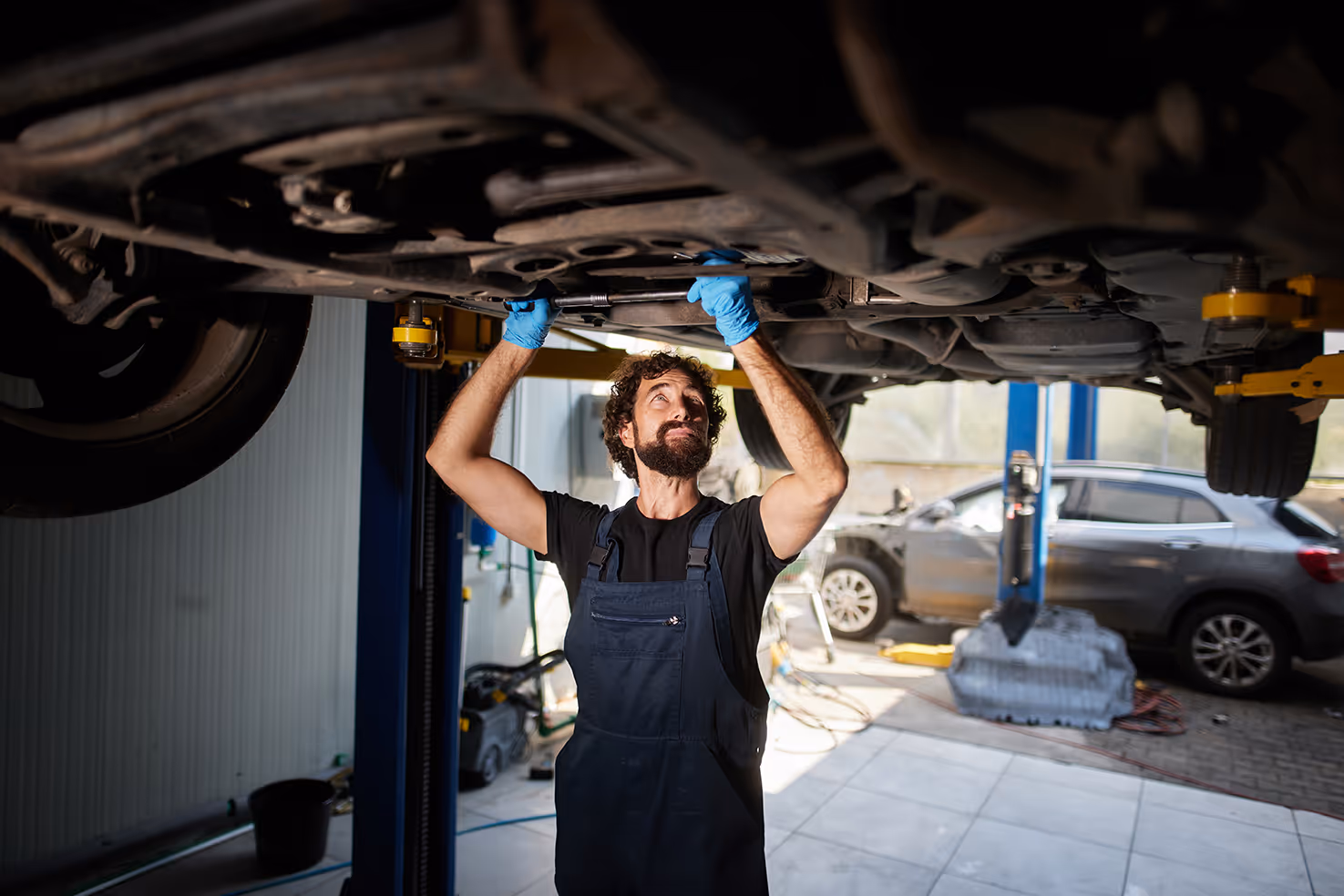 Mechanic underneath a vehicle inspecting the transmission