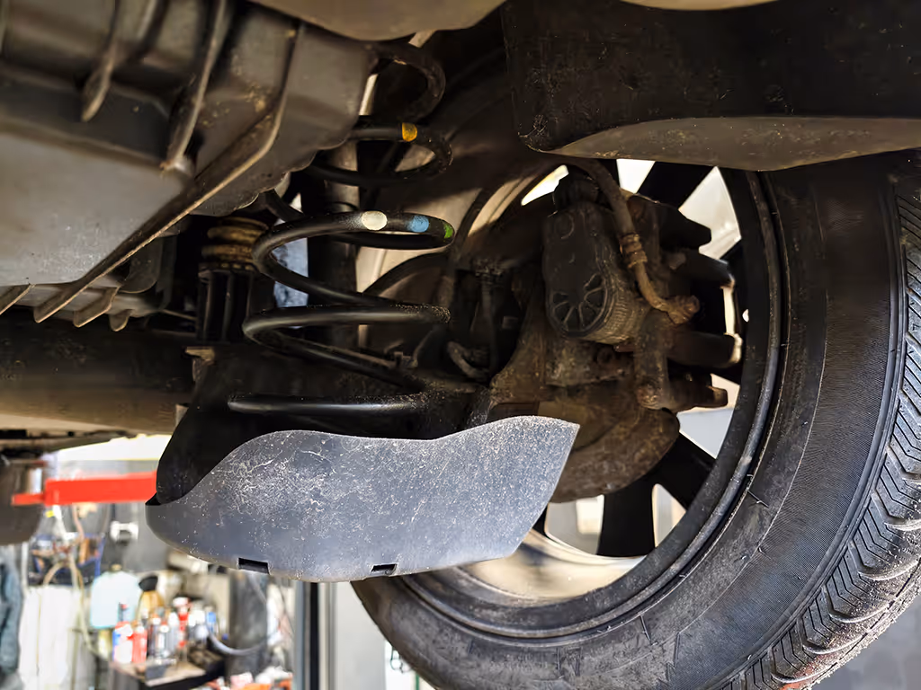 Mechanic inspecting a suspension spring and shock absorber on a vehicle