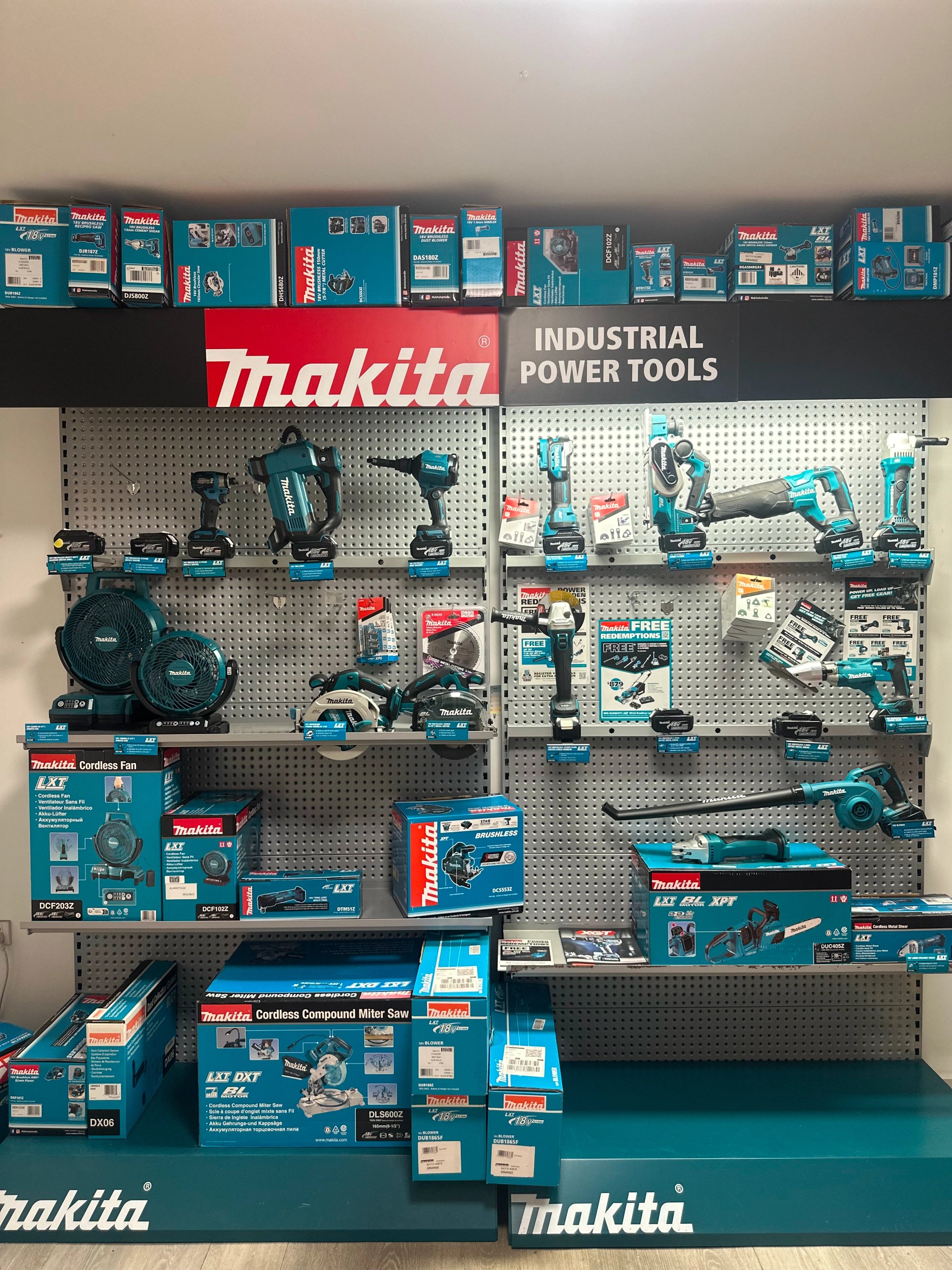 Wall display of various blue Makita industrial power tools and boxed products with Makita branding.