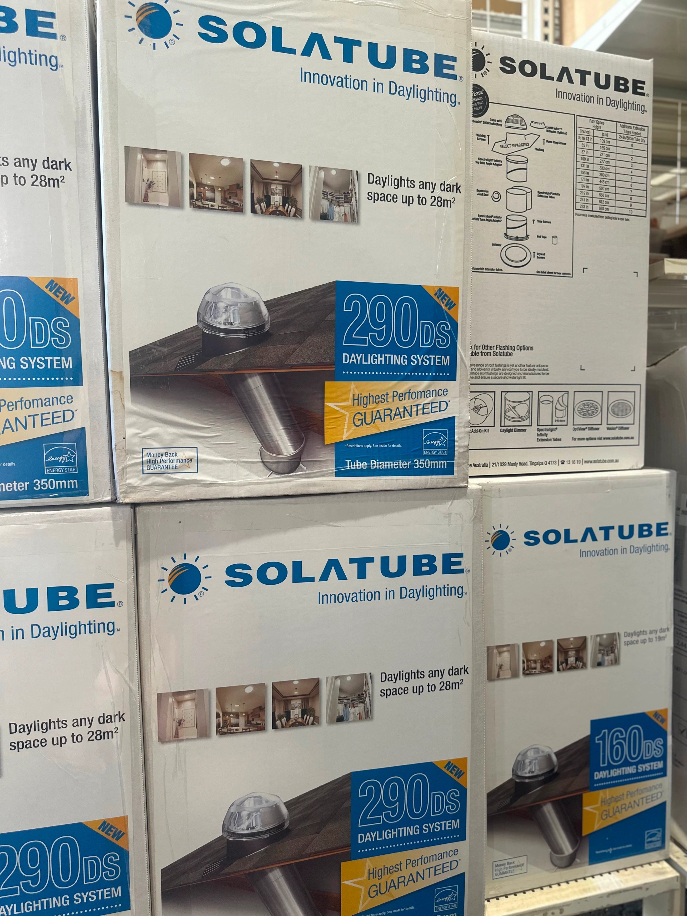 Stacked boxes of Solatube daylighting systems with product images and specifications, featuring 290DS and 160DS models for brightening dark spaces.