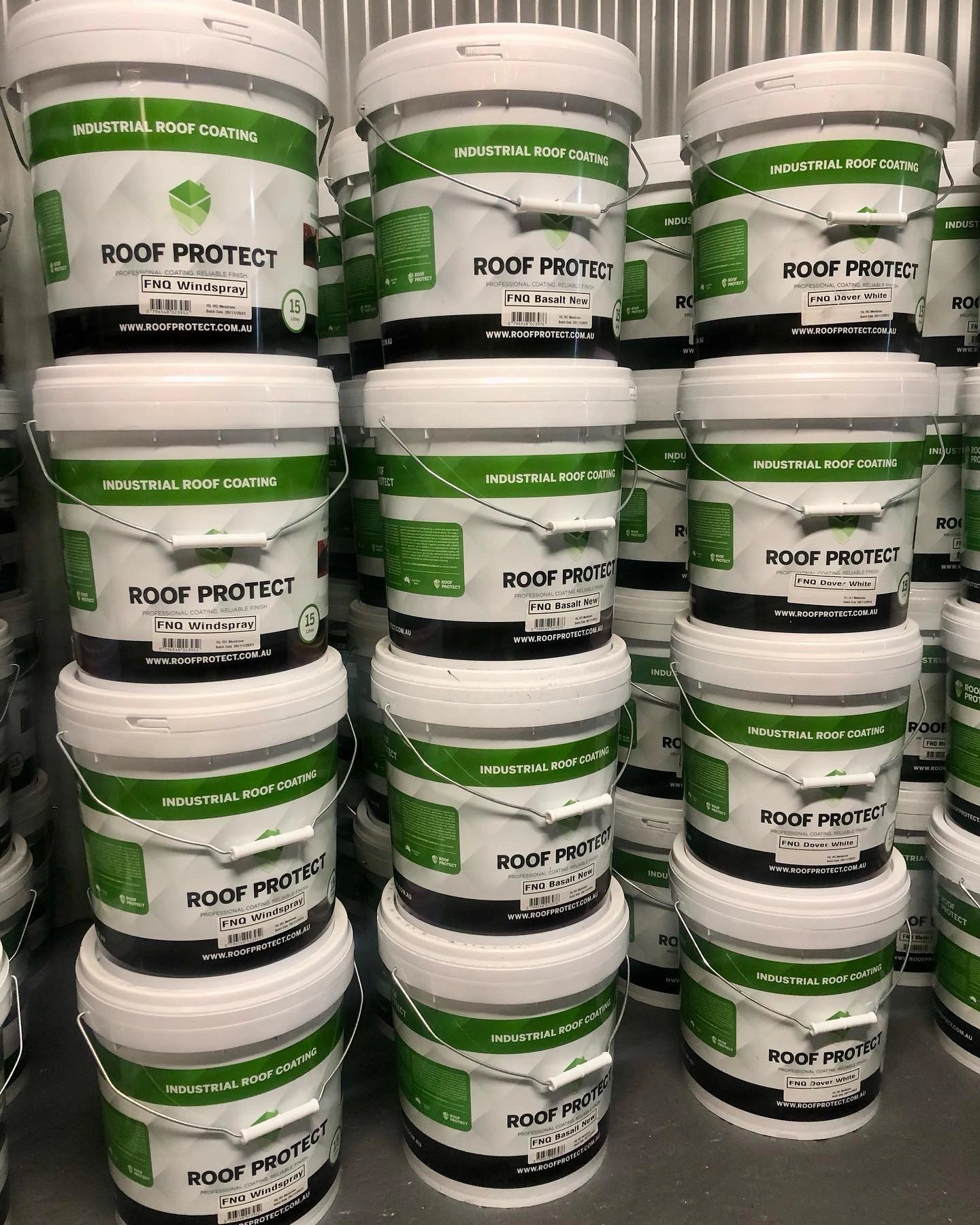 Stacked white buckets labeled Roof Protect Industrial Roof Coating in different variants including FNQ Windspray, FNQ Basalt New, and FNQ Dover White.