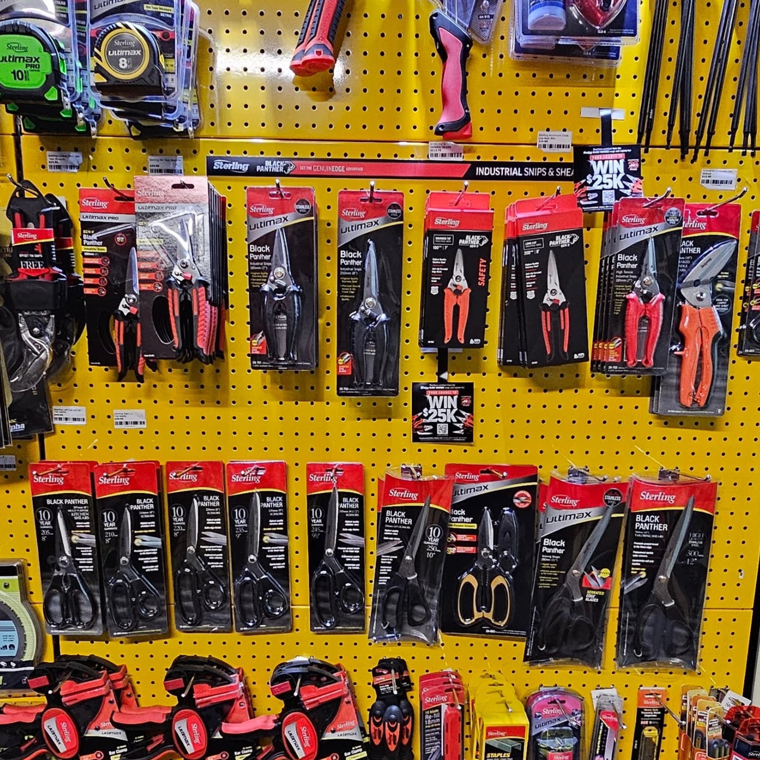 Display of various Sterling Black Panther and Ultimax branded snips, shears, scissors, and clamps on a yellow pegboard wall in a hardware store.