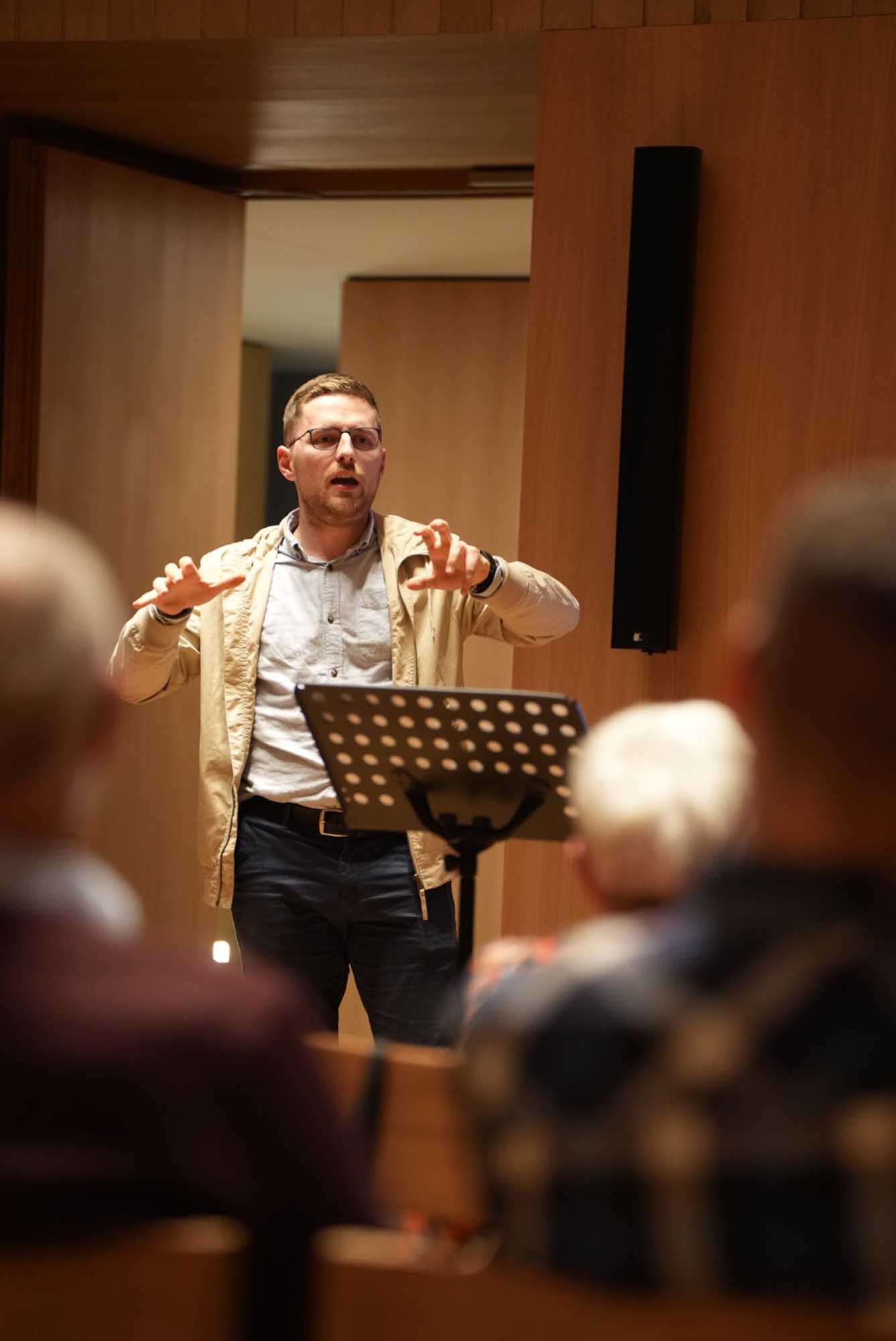 Eine Person steht an einem Rednerpult und gestikuliert beim sprechen.