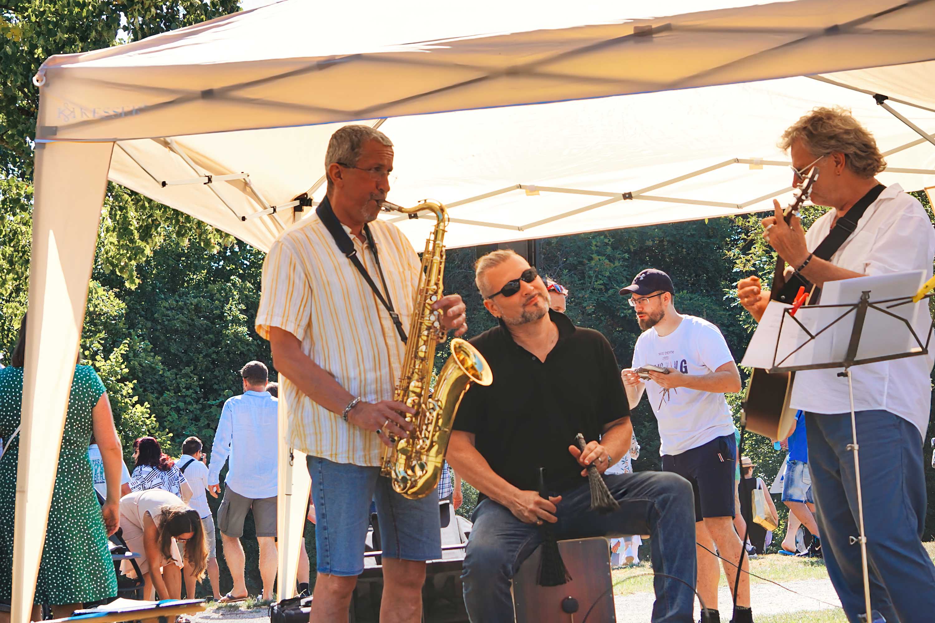 Eine Band steht unter einem Festzelt und spielt Musik.