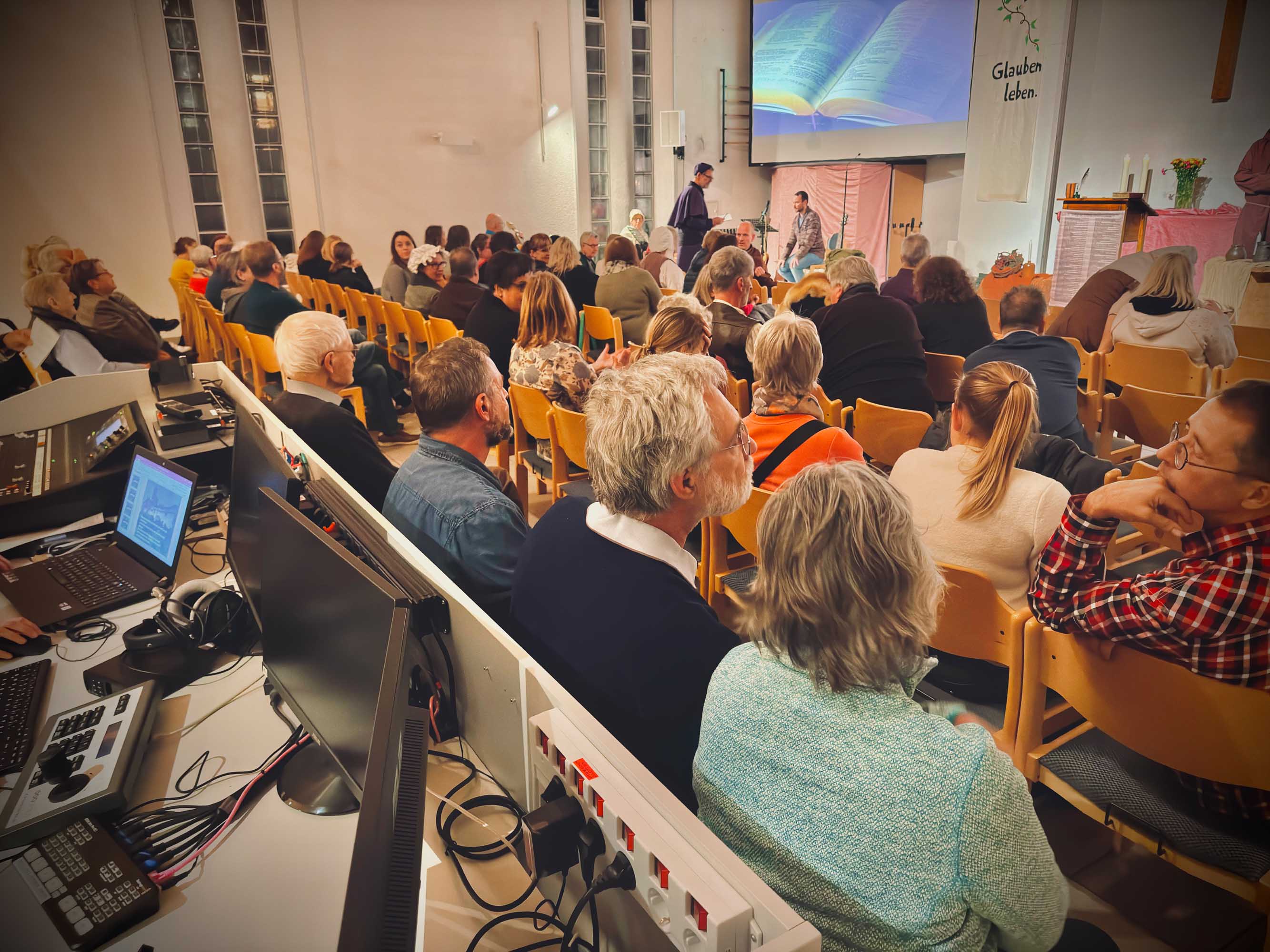 Totale eines Gottesdienstes. Viele Menschen sitzen in den Reihen.