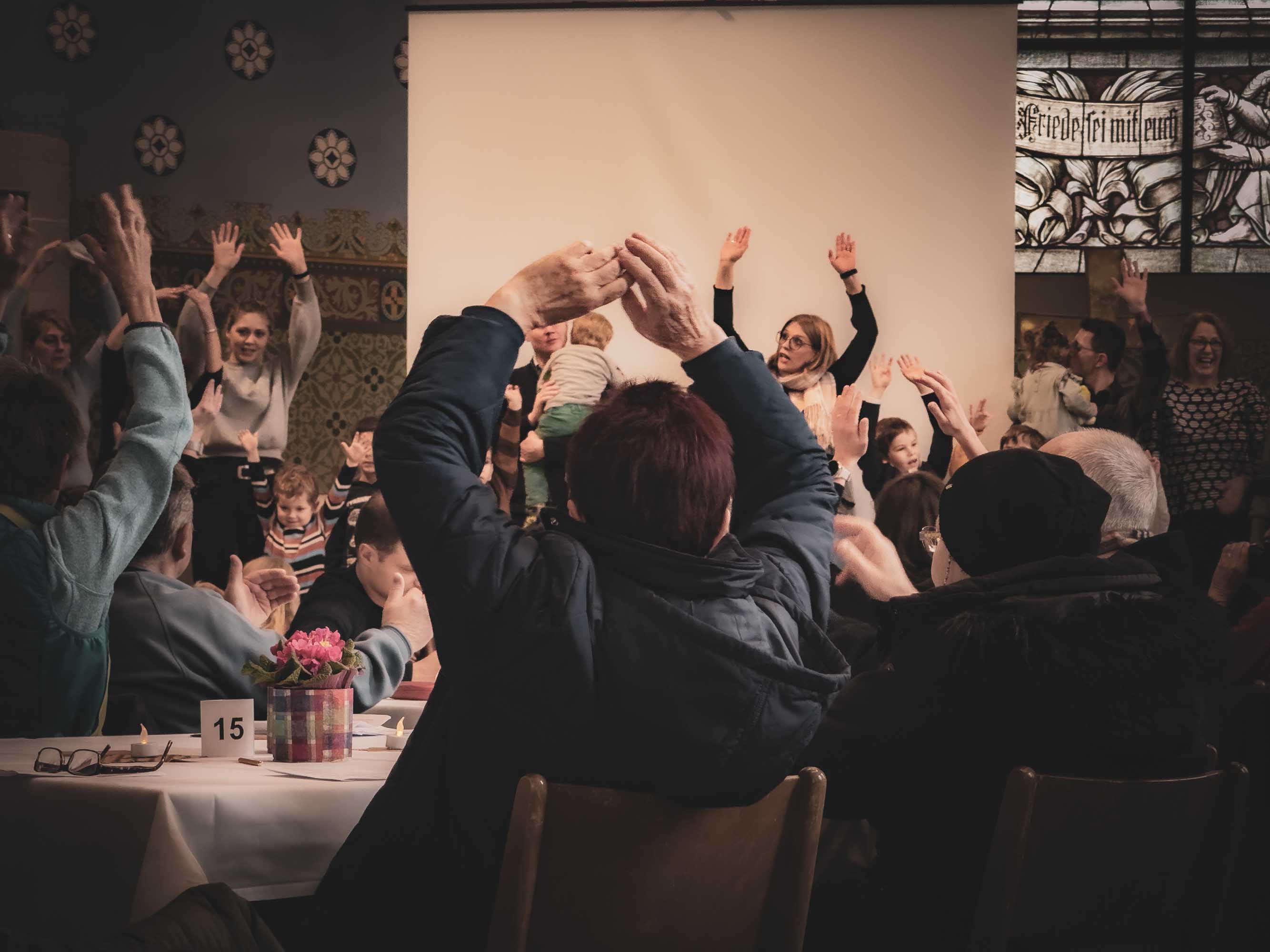 Menschen in einem Gottesdienst Setting heben die Arme und tanzen.