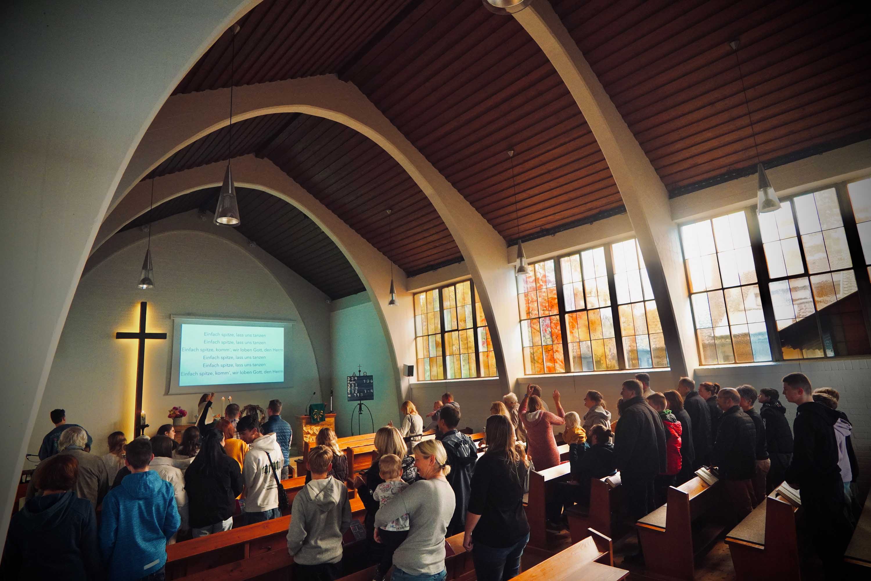 Totale eines Gottesdienstes. Viele Menschen sitzen in den Reihen.