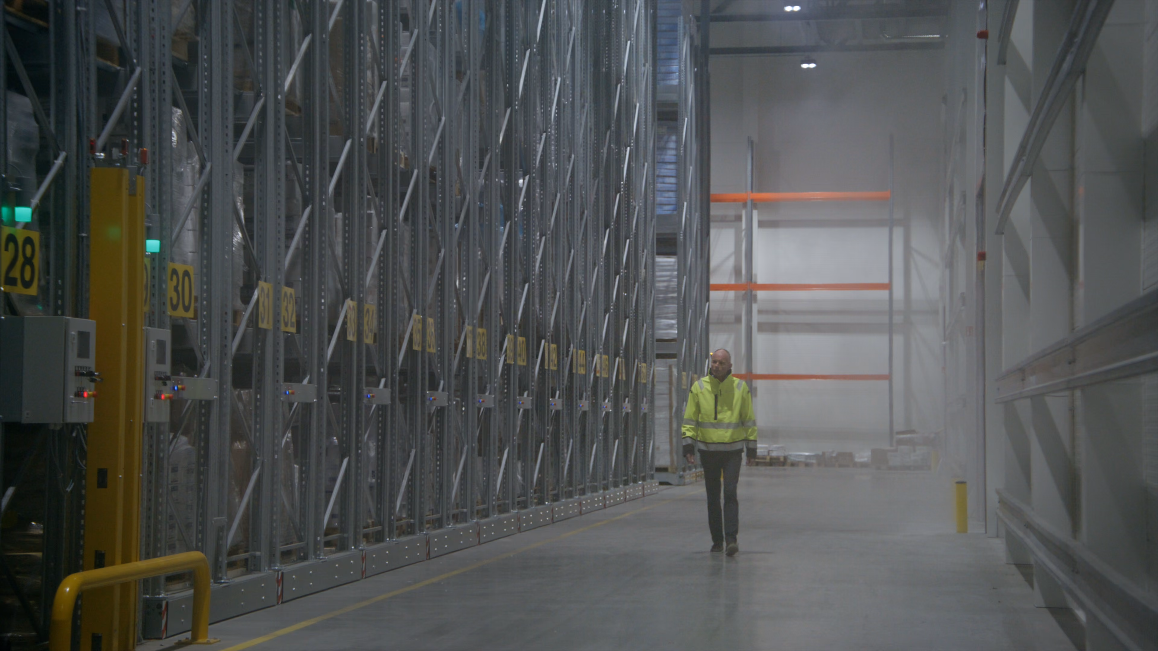 Lagerarbeider går mellom høye pallereoler