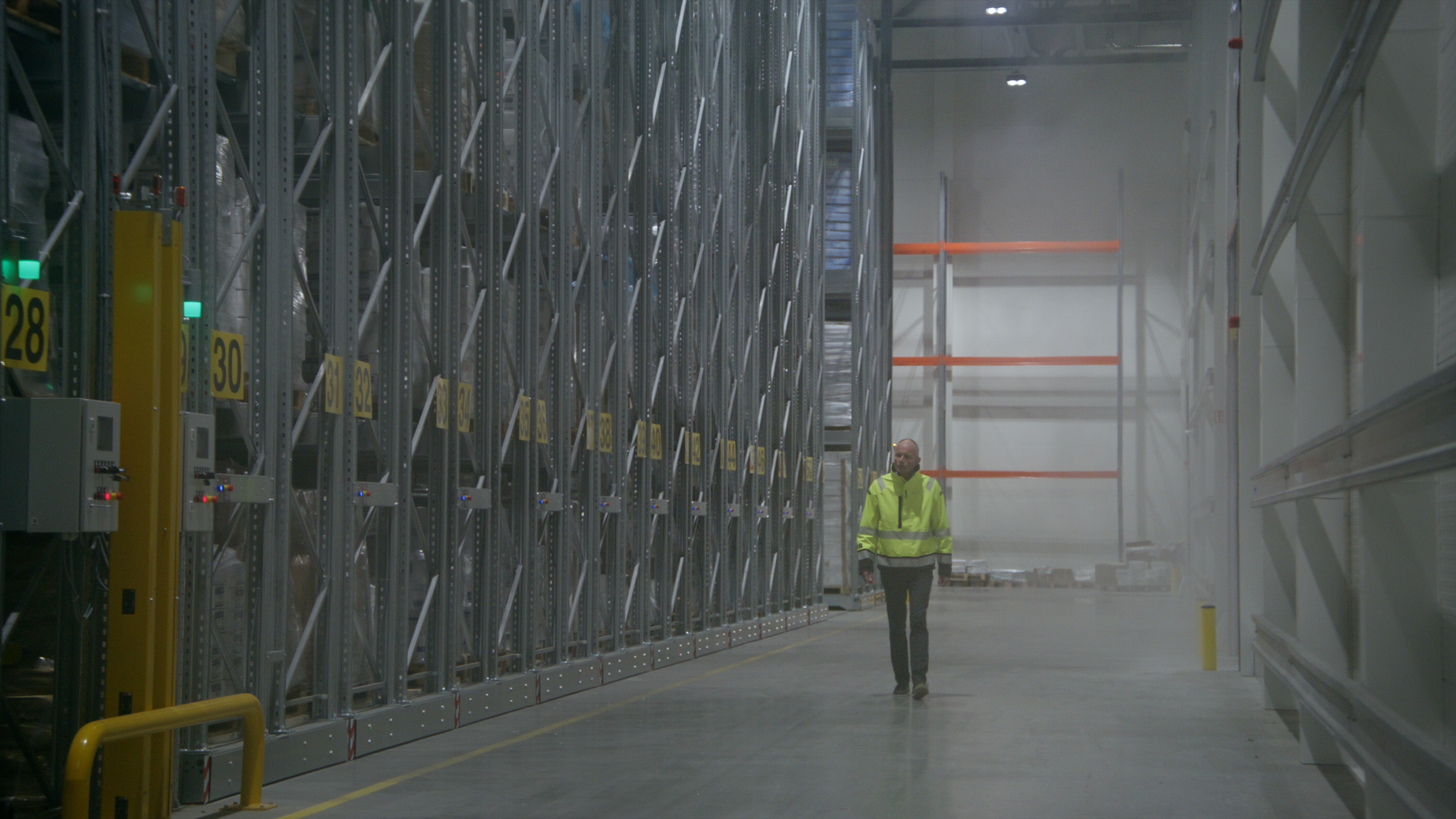 Warehouse worker walking between high pallet racks