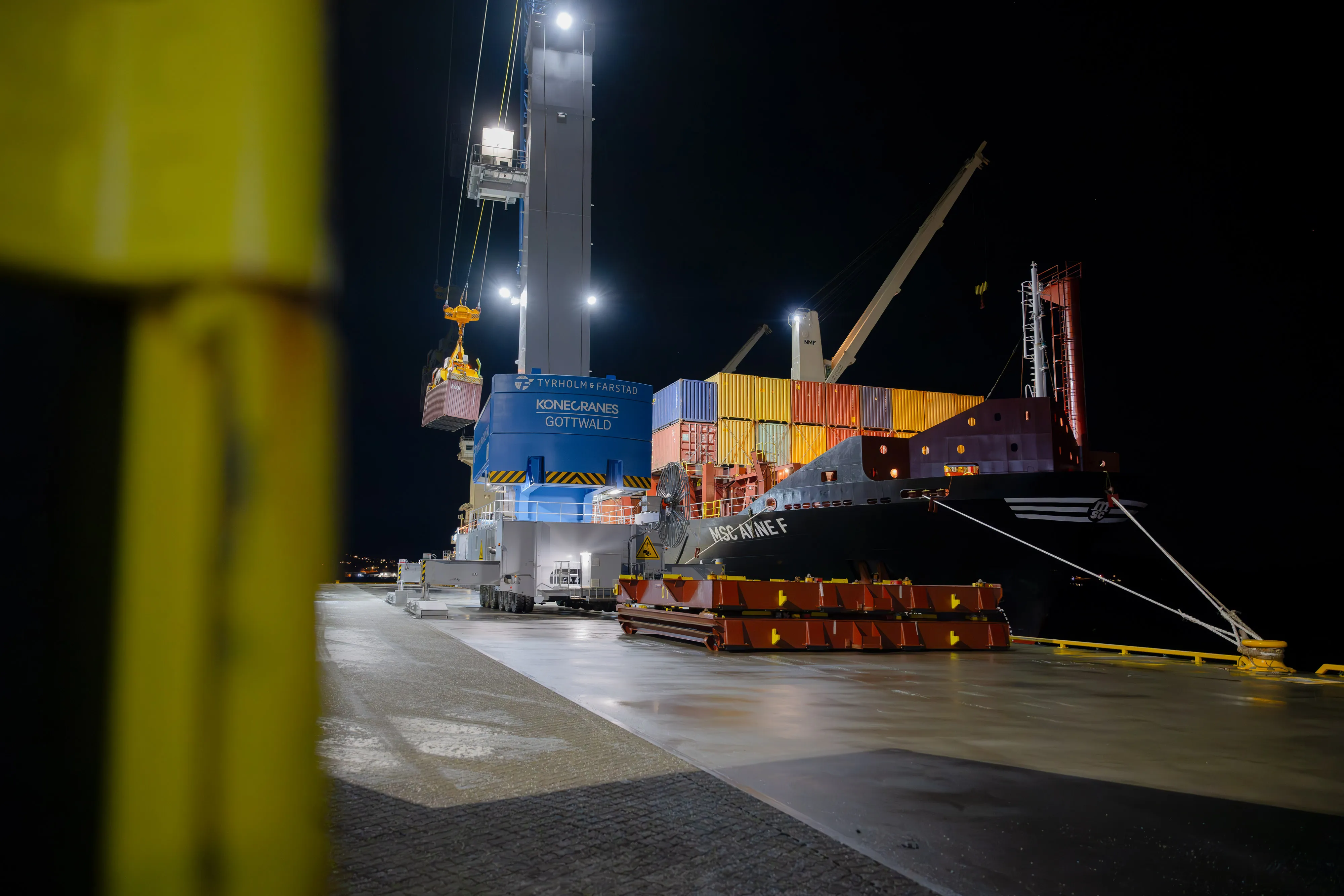 Crane lifting a container from the terminal quay at night