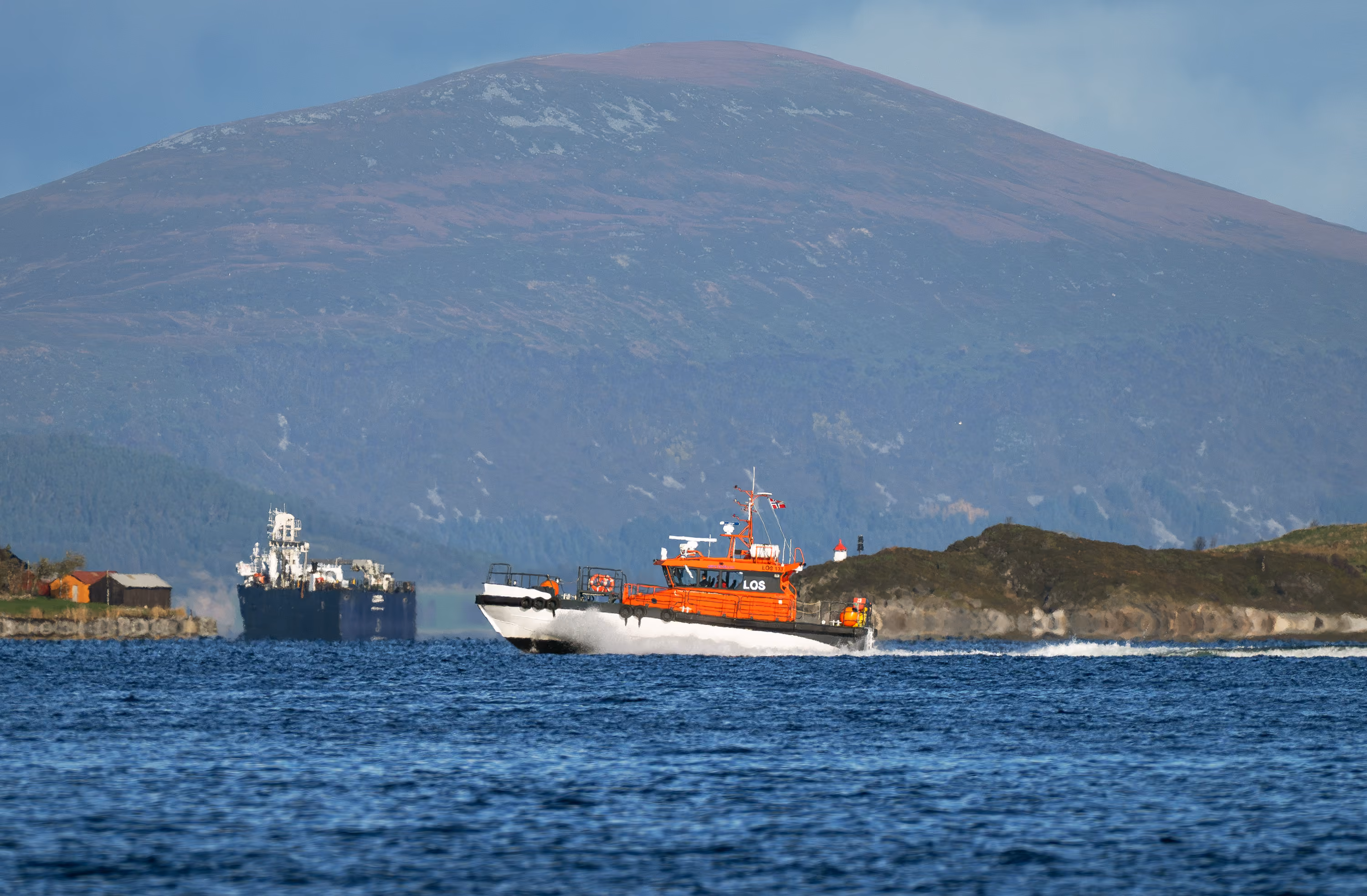 Pilot boat travelling at speed with mountains in the background