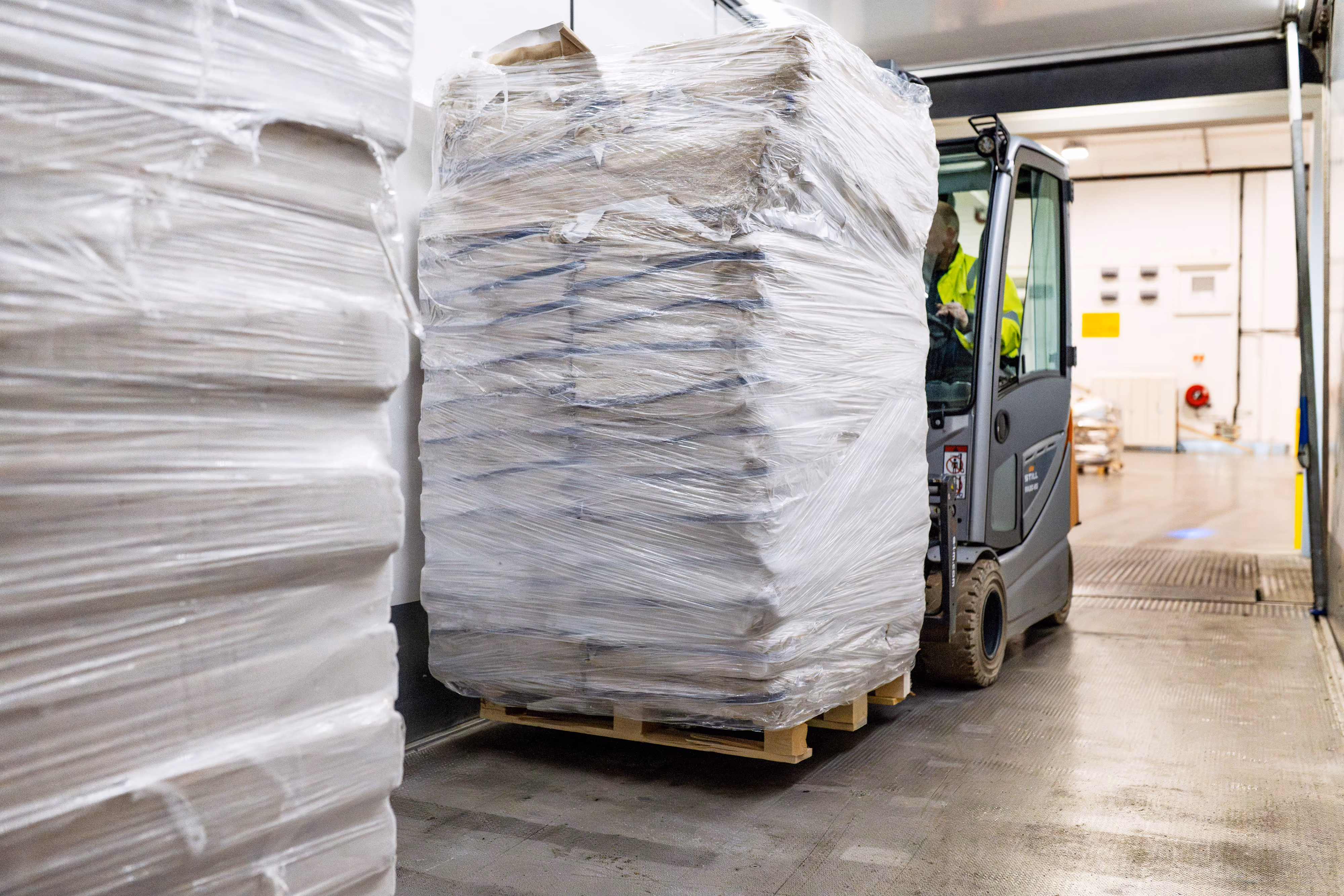 Gaffeltruck transporterer plastinnpakkede varer på lageret